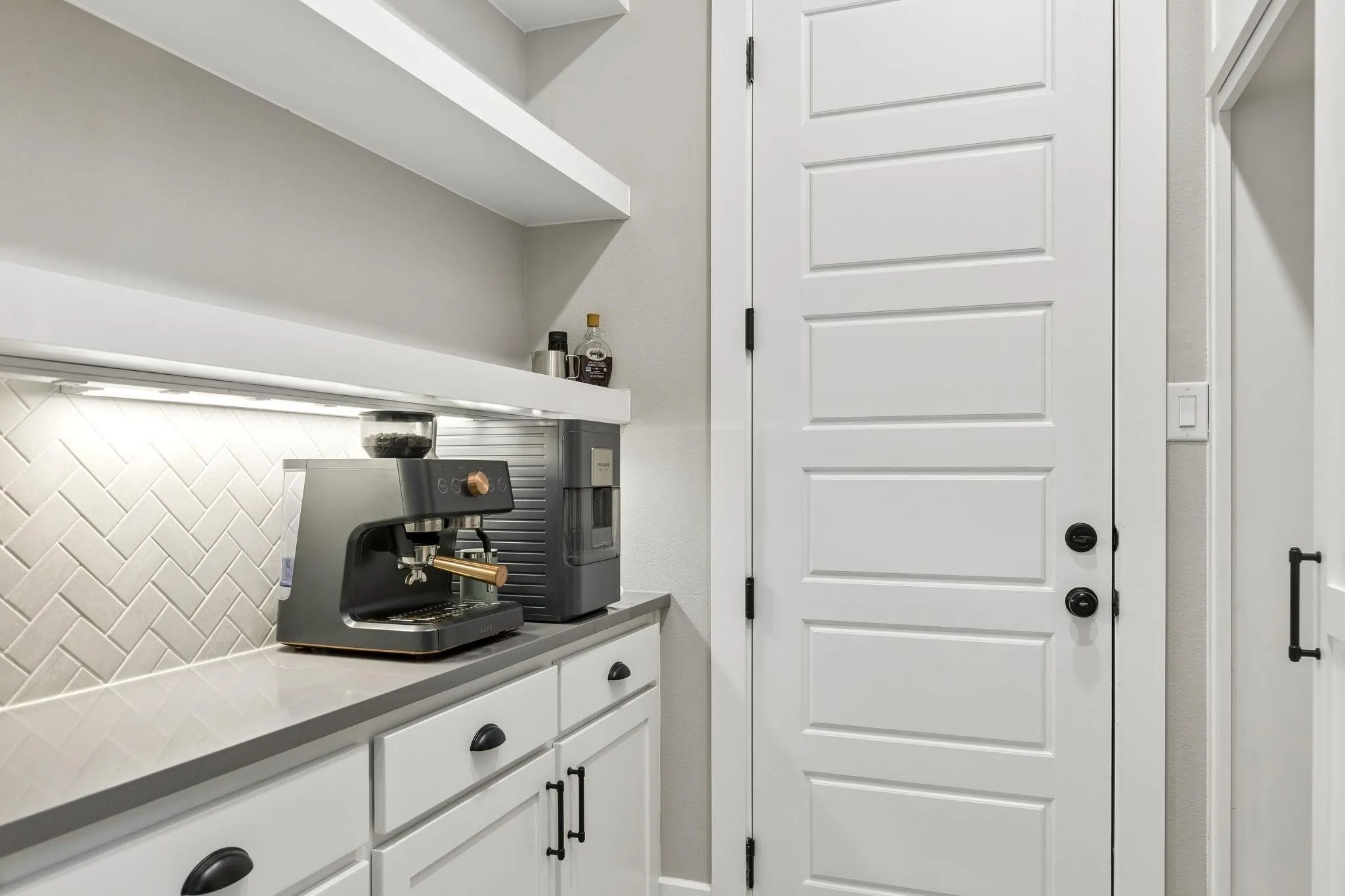 White paneled door with black hardware, complementing the white shaker-style cabinetry