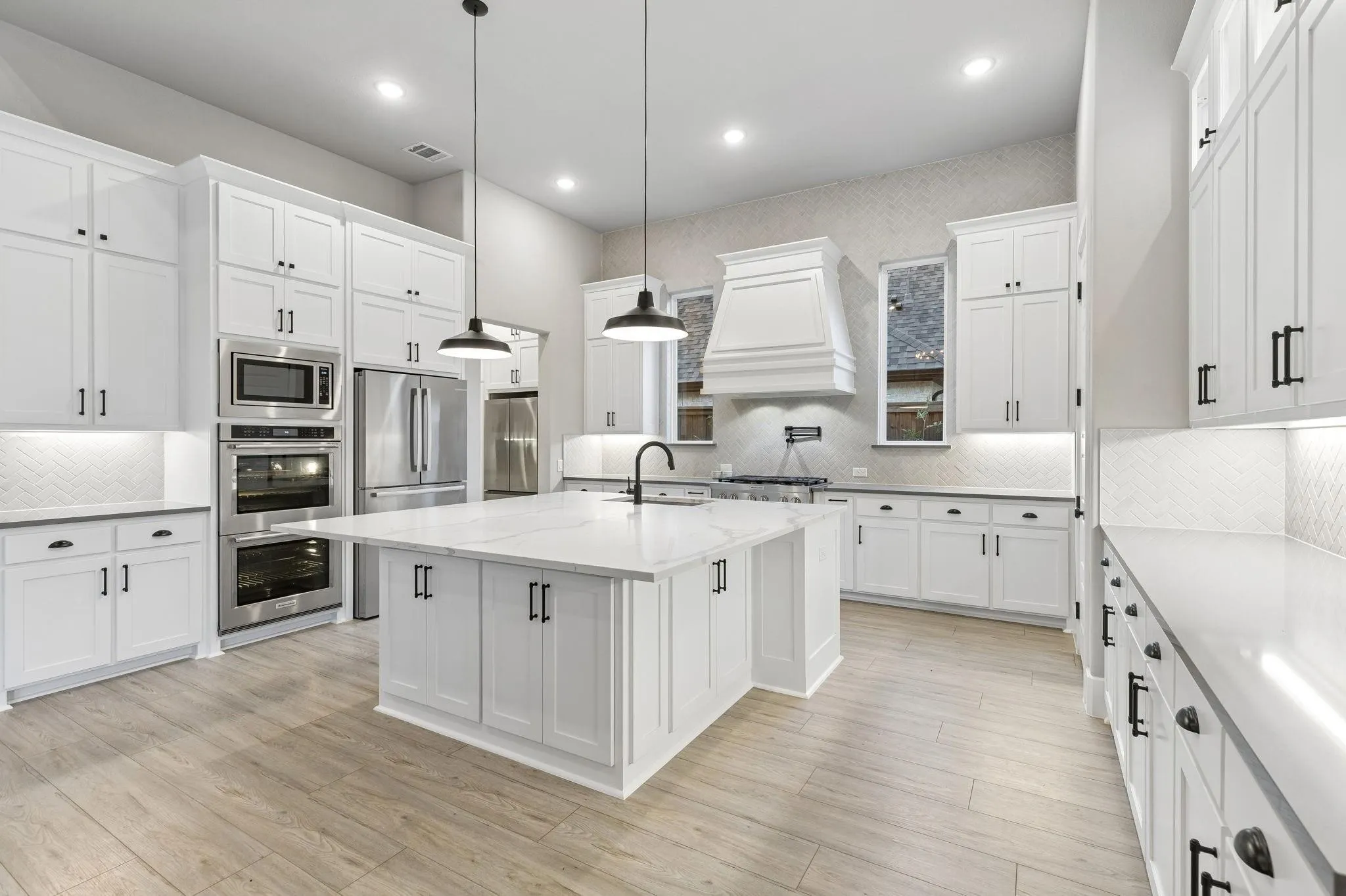 Kitchen featuring white cabinetry, wood-finish flooring, stainless steel appliances, a center island with a white countertop, and recessed lighting