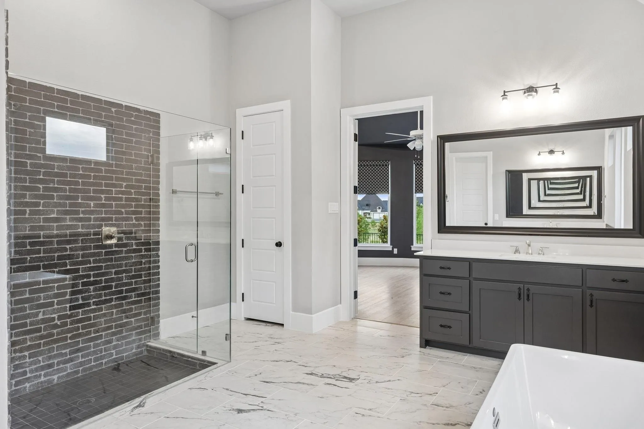 Glass-enclosed shower with brick-finish wall and built-in bench