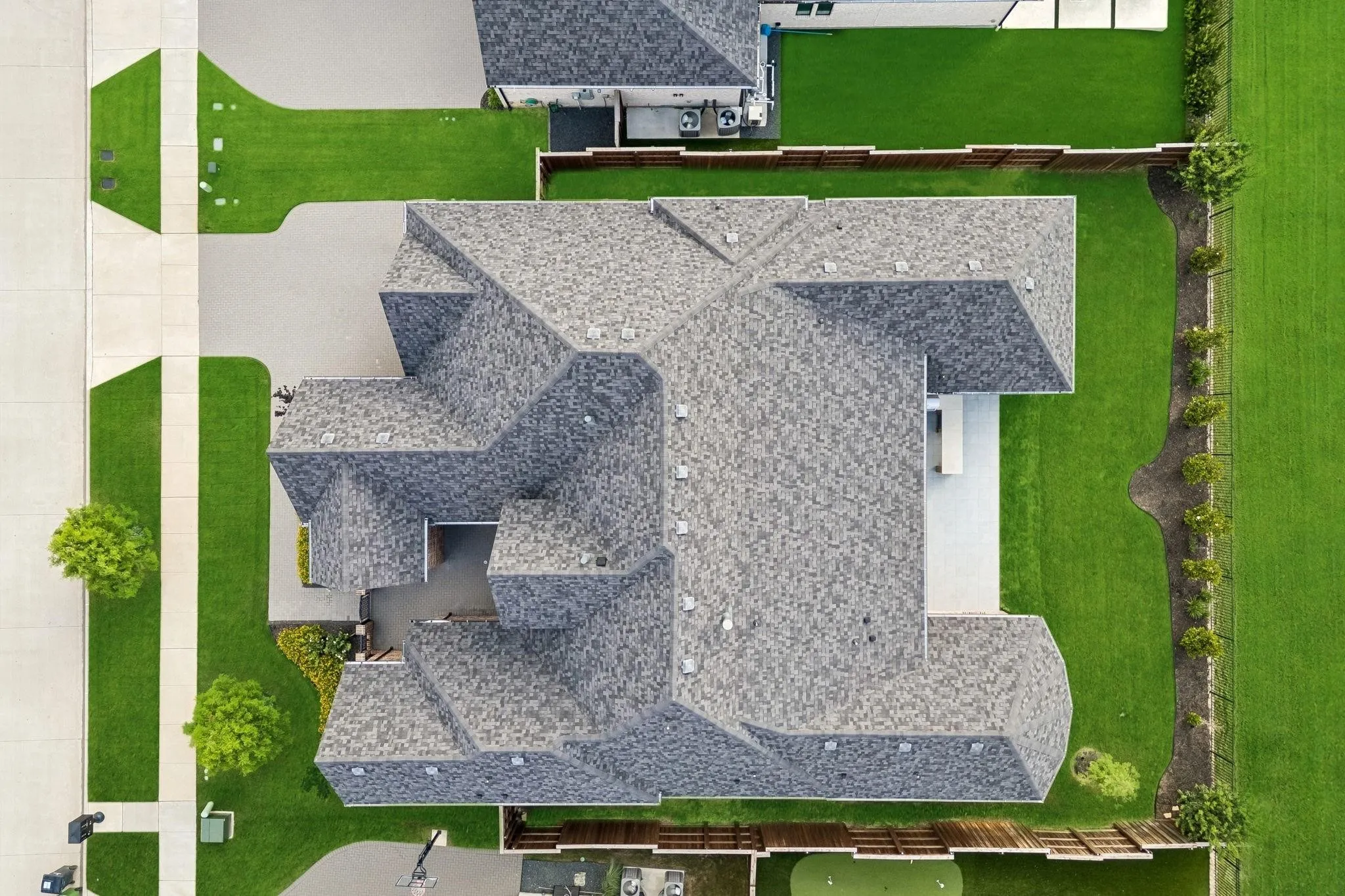 Expansive property featuring a multi-gabled roofline, concrete driveway, concrete sidewalks, and manicured green spaces