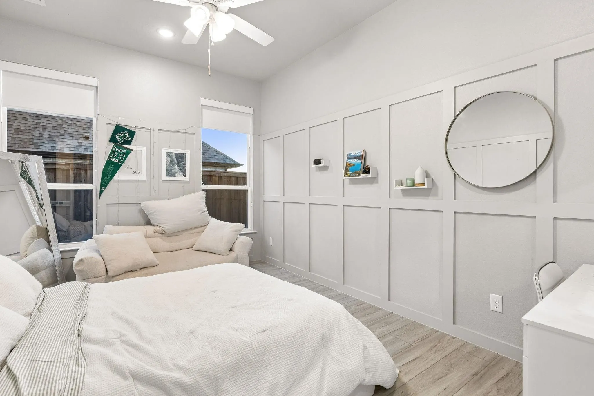 Board and batten wall detailing, wood-finish flooring, two window openings, ceiling fan fixture, and recessed lighting
