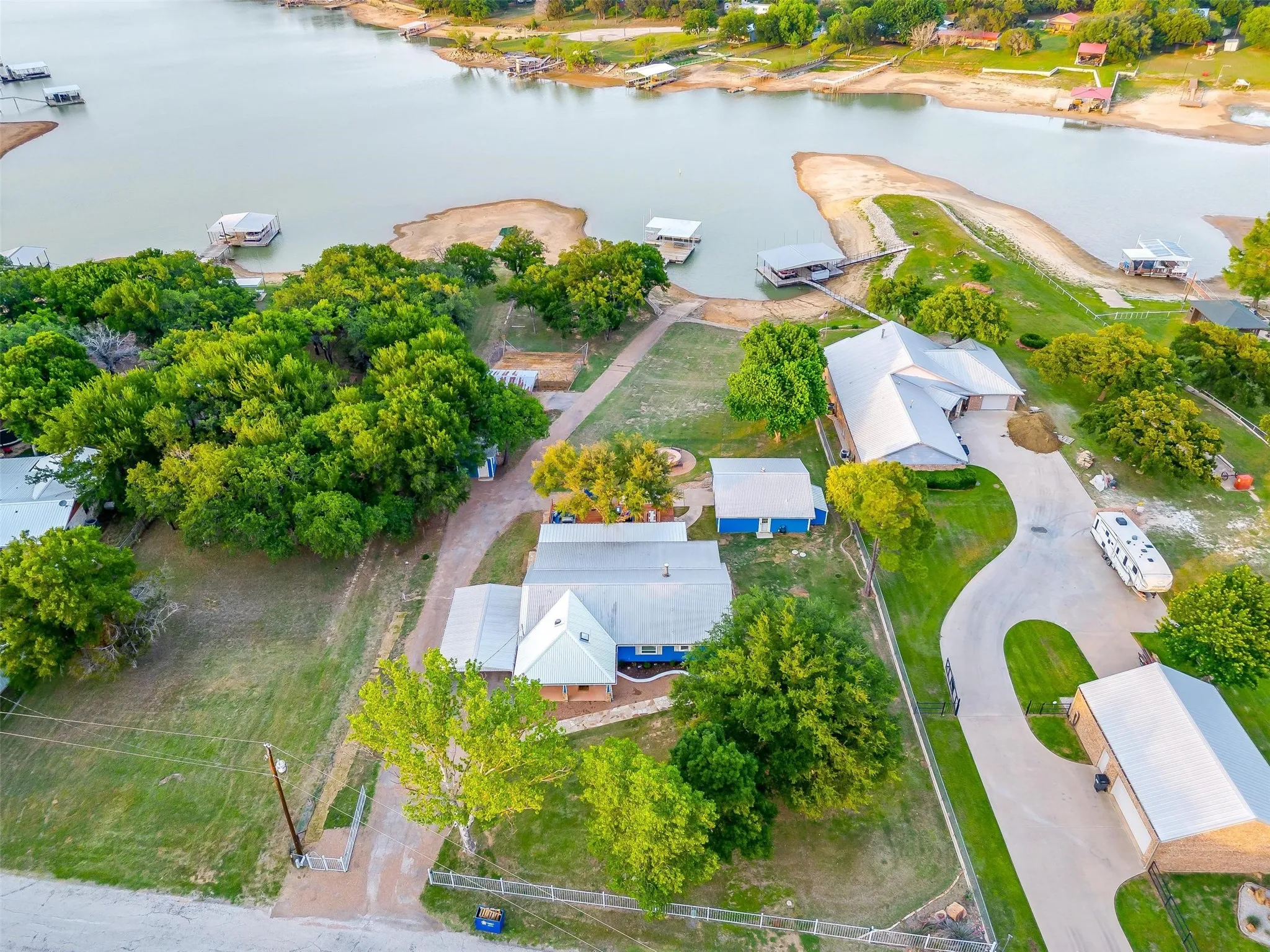 Waterfront property with multiple boat docks, mature trees, and a concrete driveway