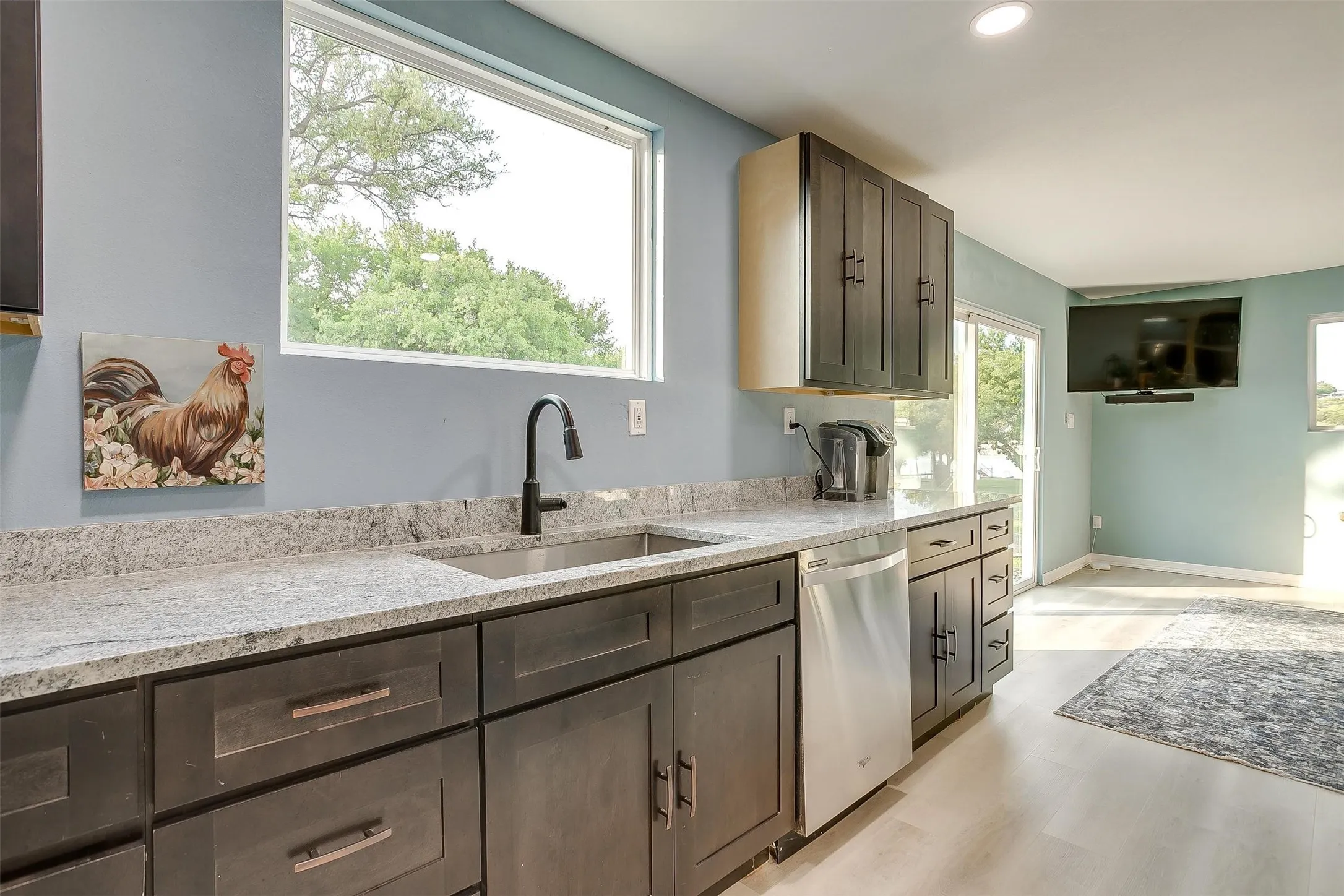 Kitchen featuring a stainless steel sink, dark wood-finish cabinetry, light-toned countertop, and recessed lighting