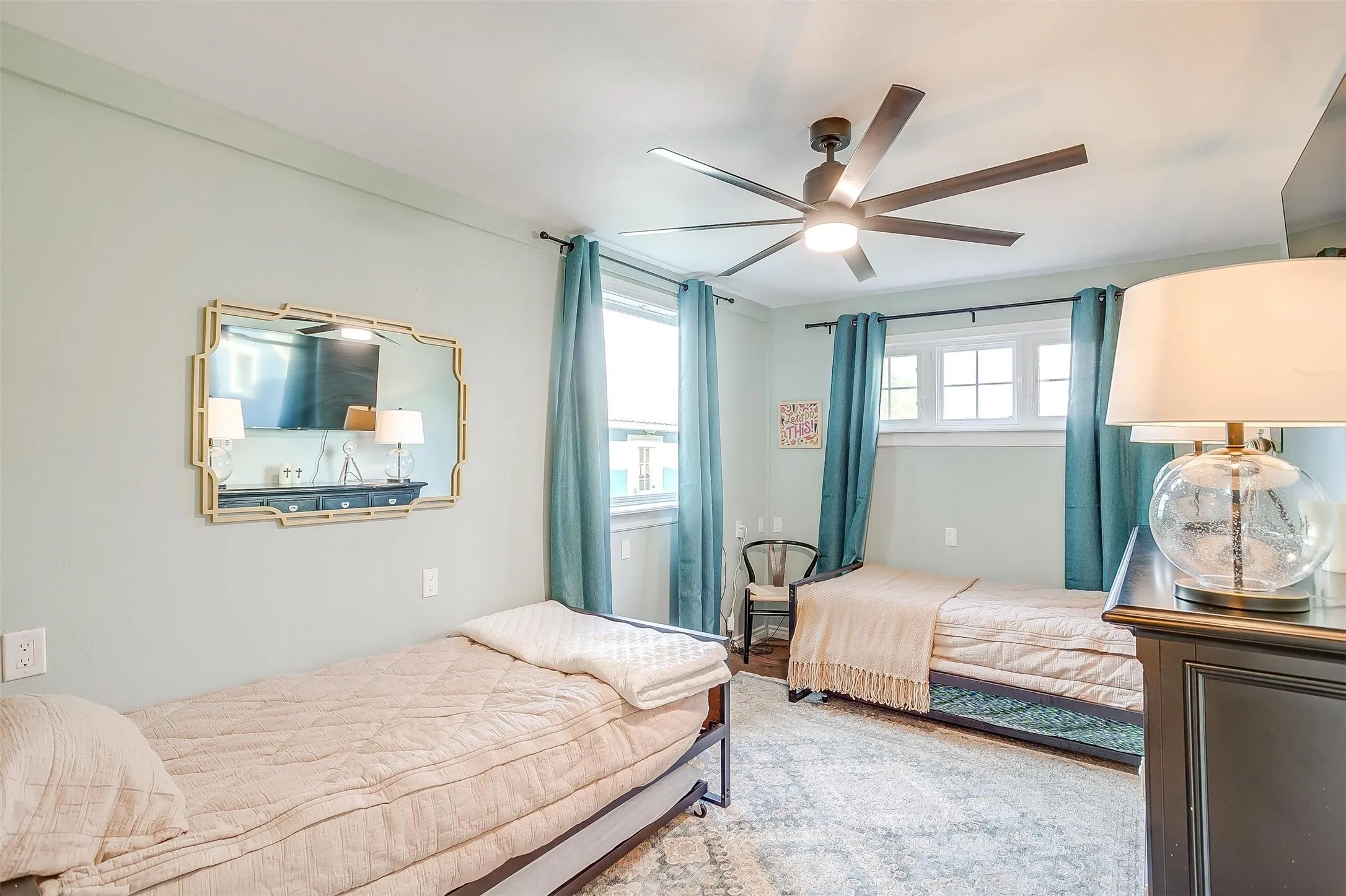 Ceiling fan with integrated lighting, multiple windows, window treatments, and wall-mounted mirror