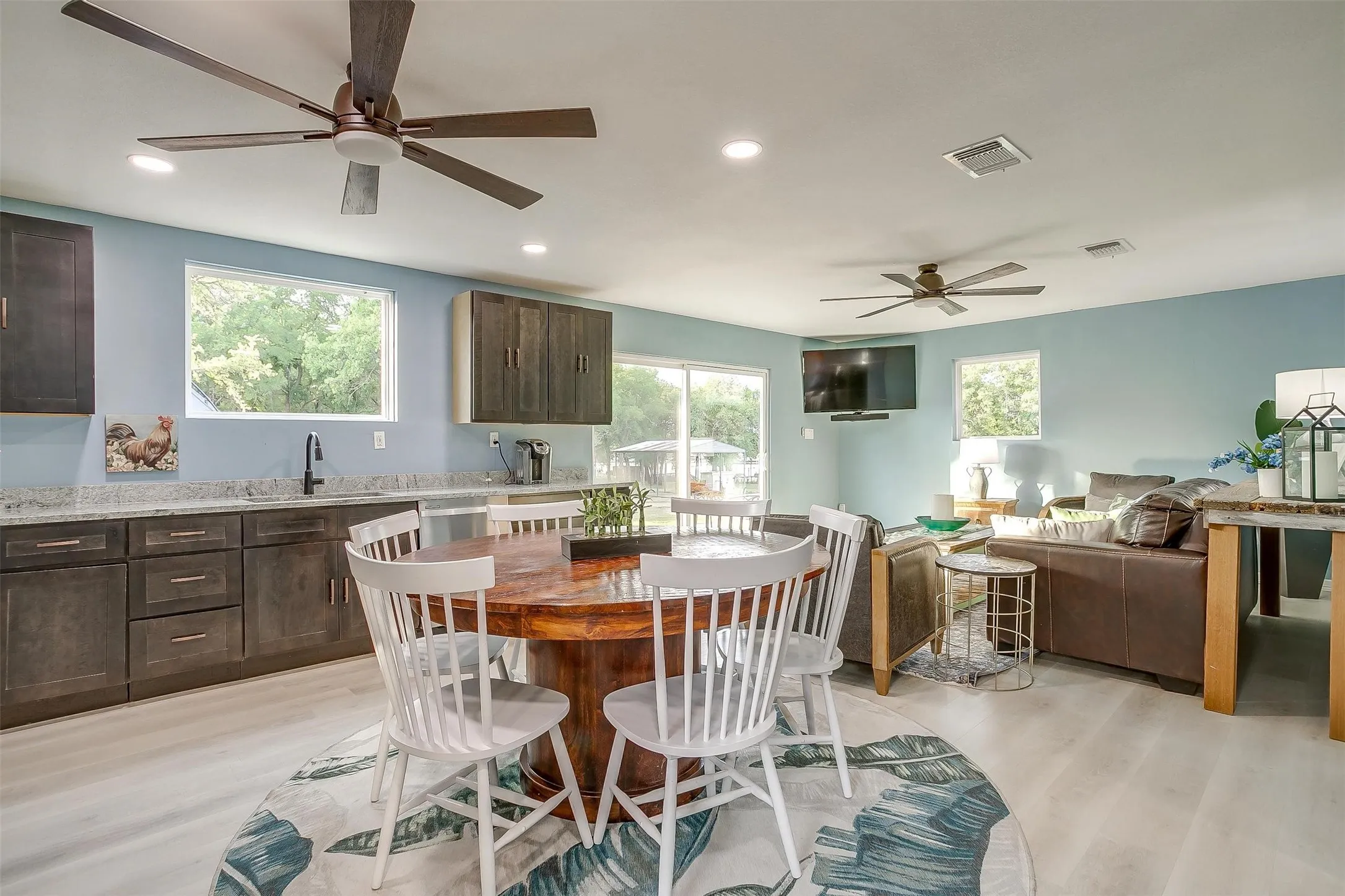 Open-concept living area with light-toned flooring, recessed lighting, and ceiling fans