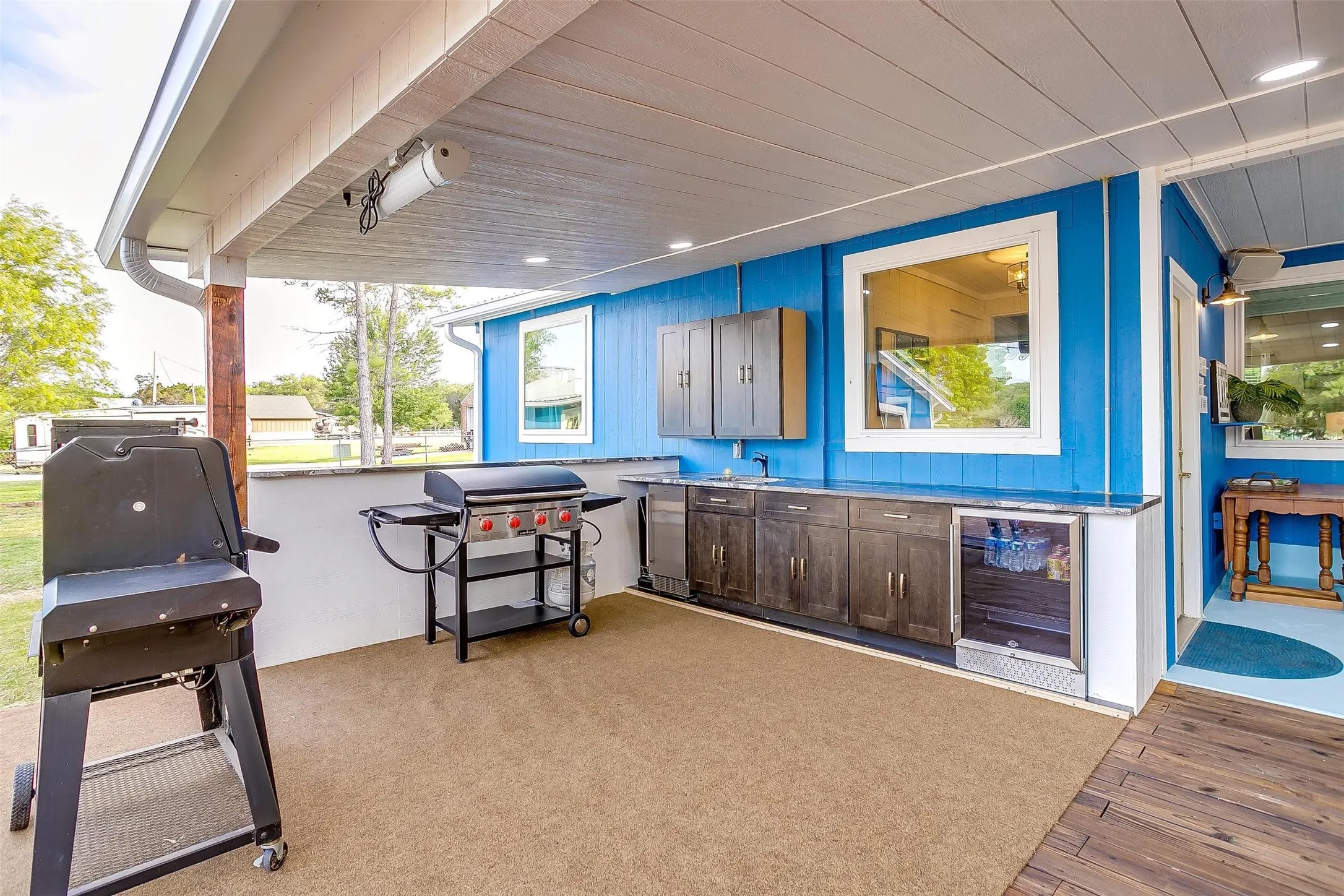 Covered patio with integrated outdoor kitchen, built-in cabinetry, beverage refrigerator, and wood-finish flooring
