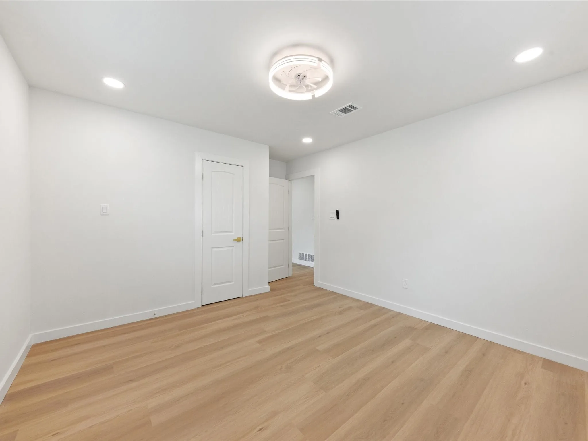 Recessed lighting, wood-finish flooring, and white walls