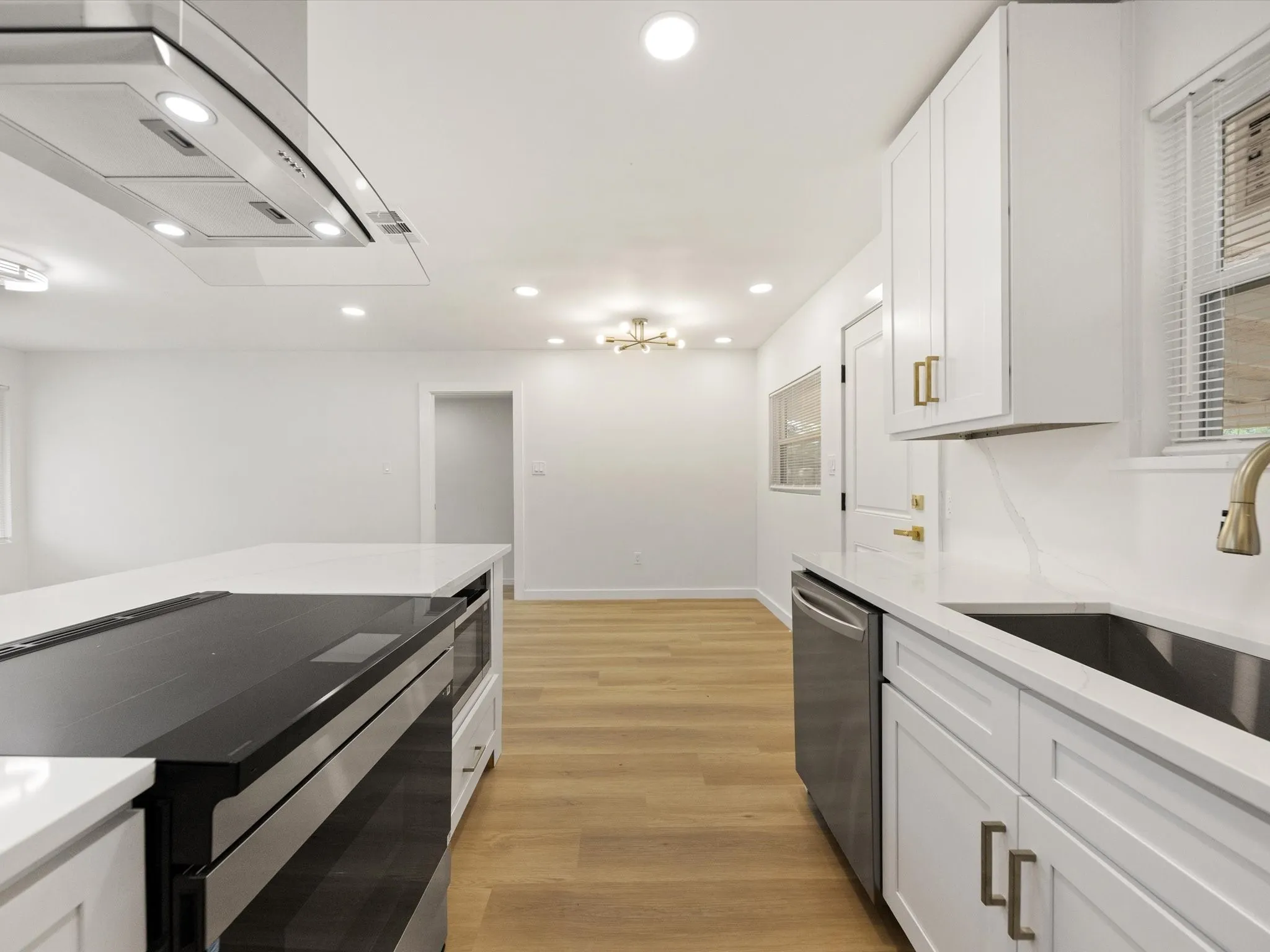 White shaker cabinetry, stainless steel appliances, white countertops, recessed lighting, and wood-finish flooring