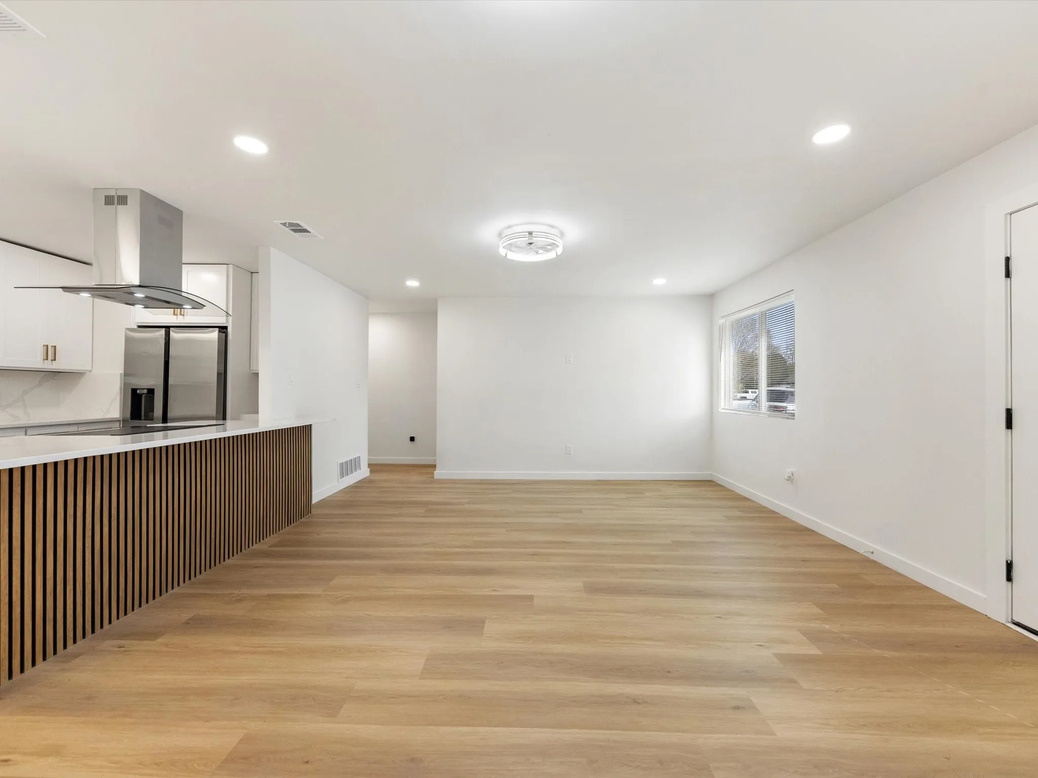 Open-concept living area with wood-finish flooring, recessed lighting, and a modern ceiling fixture