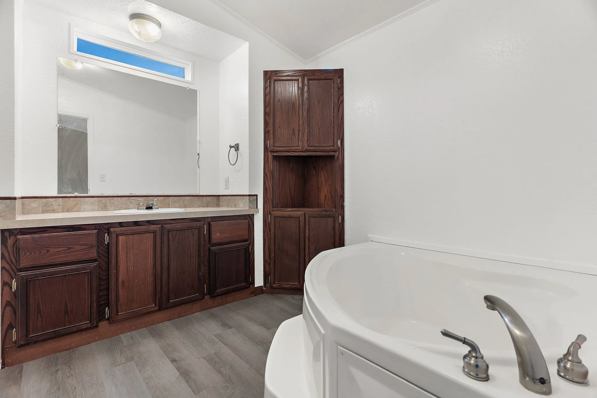 Bathroom featuring wood-type flooring, a tub to relax in, vanity, and ornamental molding