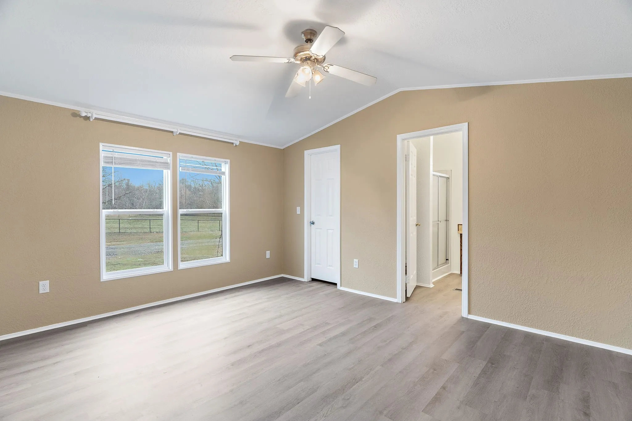 Unfurnished bedroom featuring ceiling fan, vaulted ceiling, and light hardwood / wood-style floors