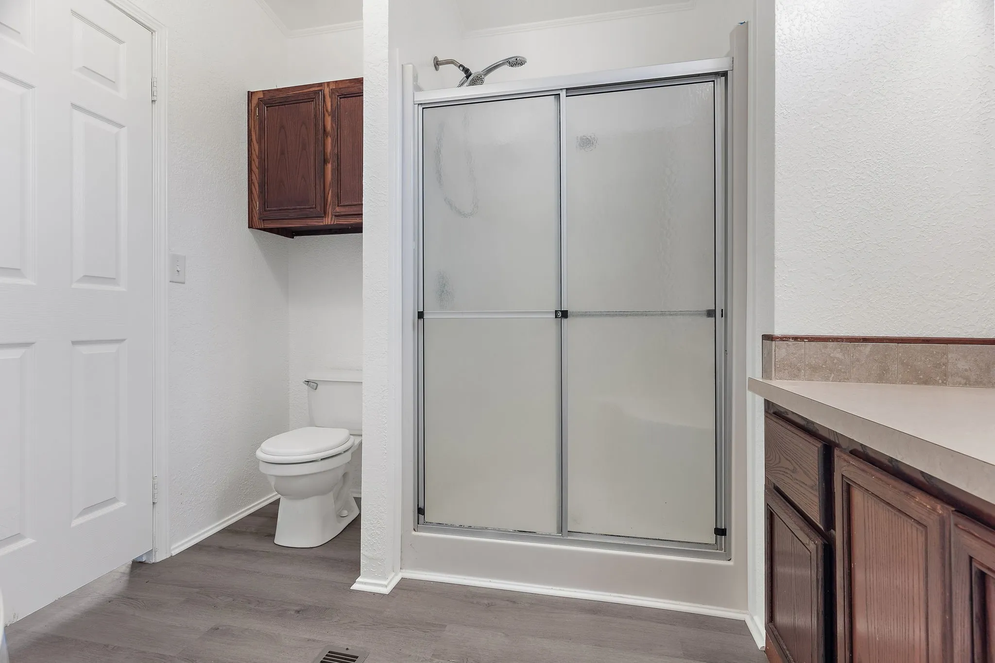 Bathroom featuring toilet, wood-type flooring, an enclosed shower, and vanity