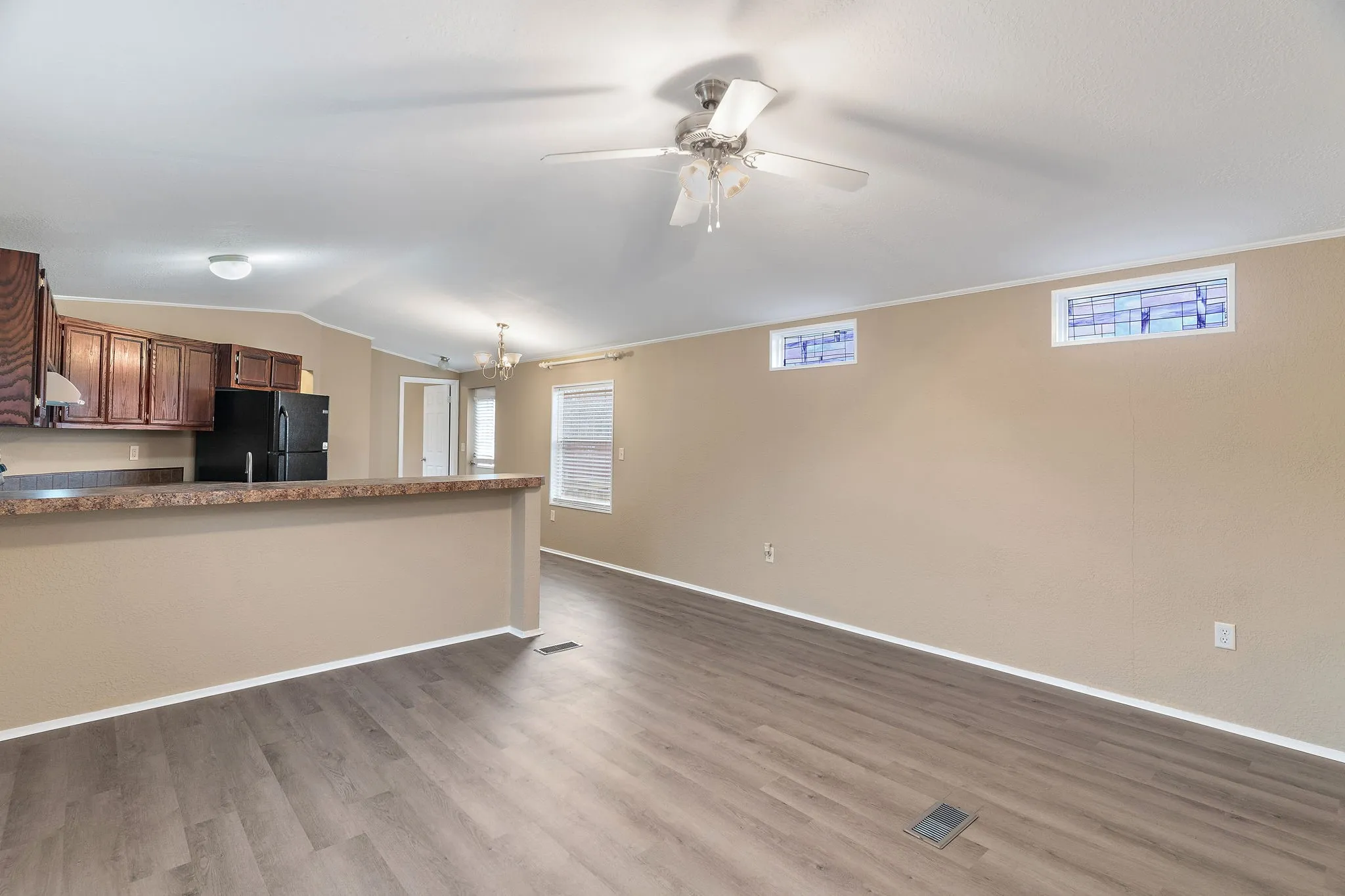 Kitchen with vaulted ceiling, hardwood / wood-style floors, plenty of natural light, and black fridge