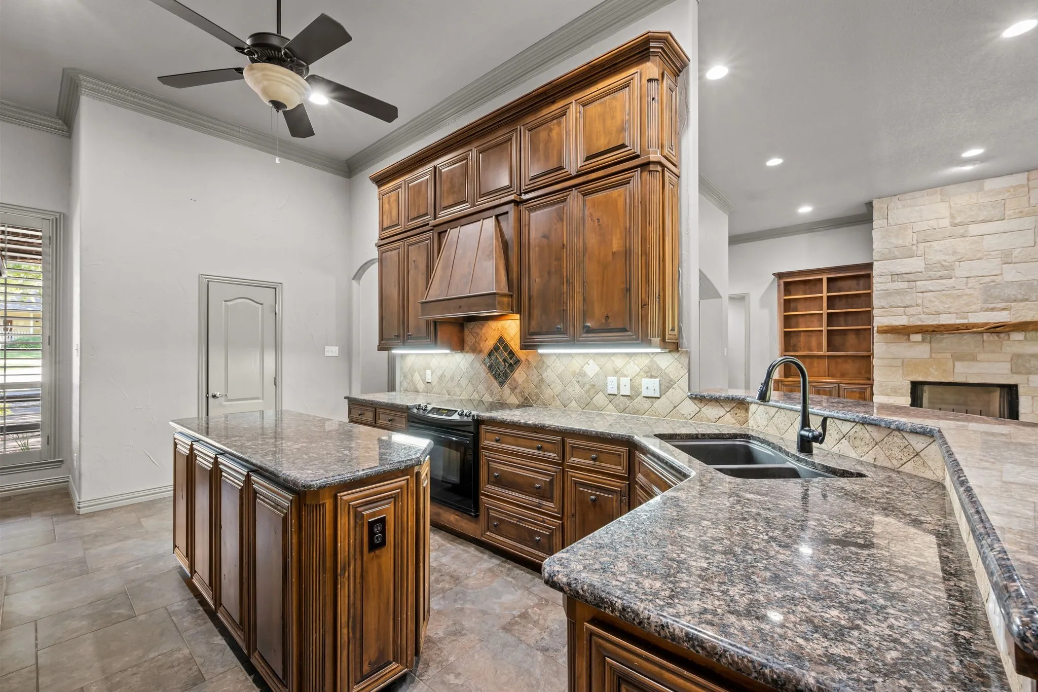 Chef's kitchen featuring custom wood cabinetry, granite countertops, a large center island with seating, stainless steel appliances, and a tile backsplash
