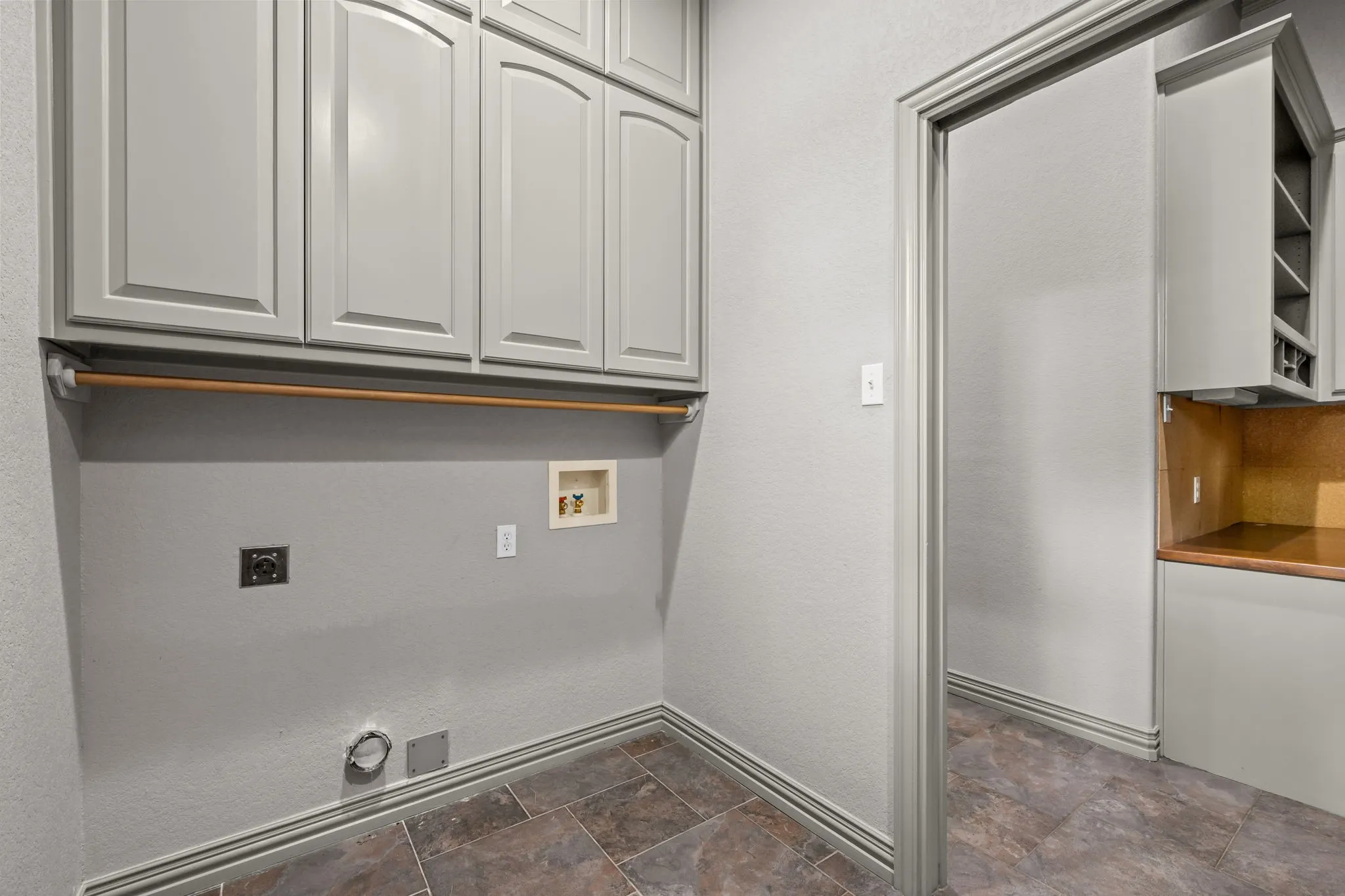 Laundry area featuring full-height upper cabinetry, a hanging rod, and tile flooring