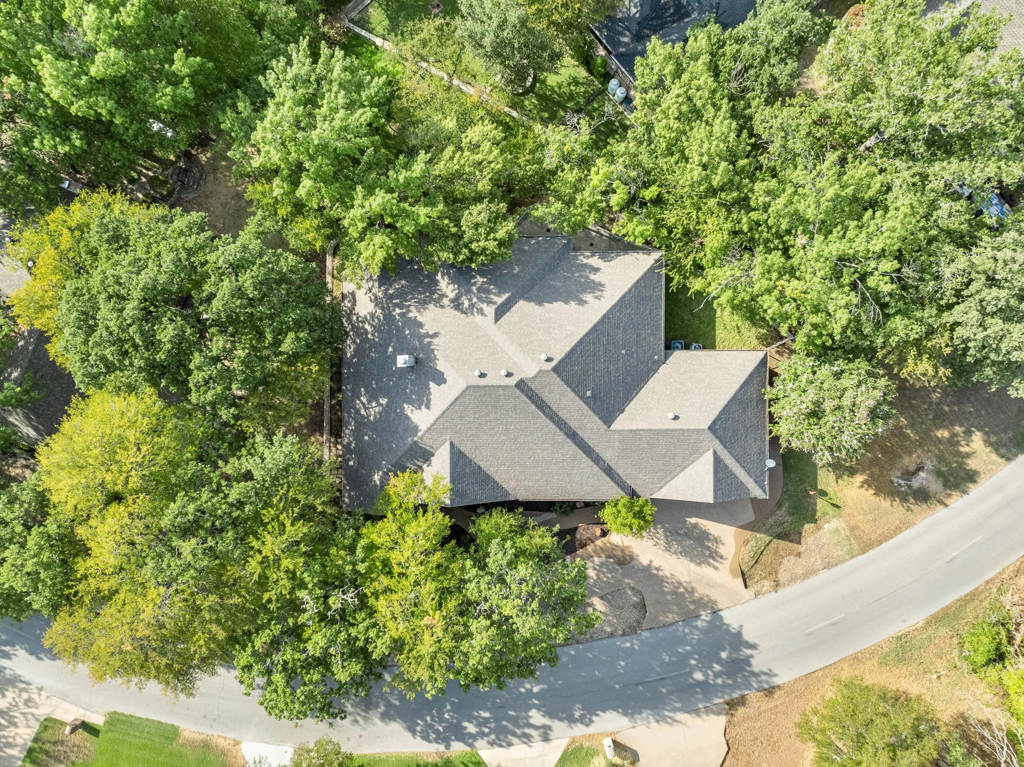 Pitched roofline with gray shingles surrounded by mature trees