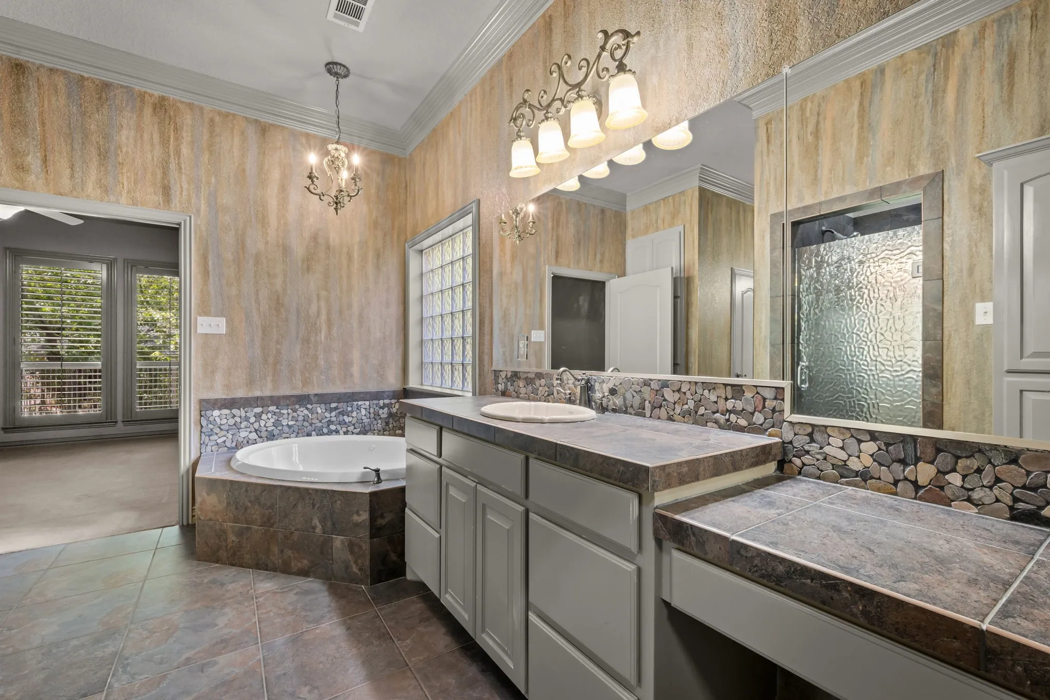 Dual vanity with integrated sinks, built-in soaking tub, tiled flooring, glass block window, and a separate shower enclosure