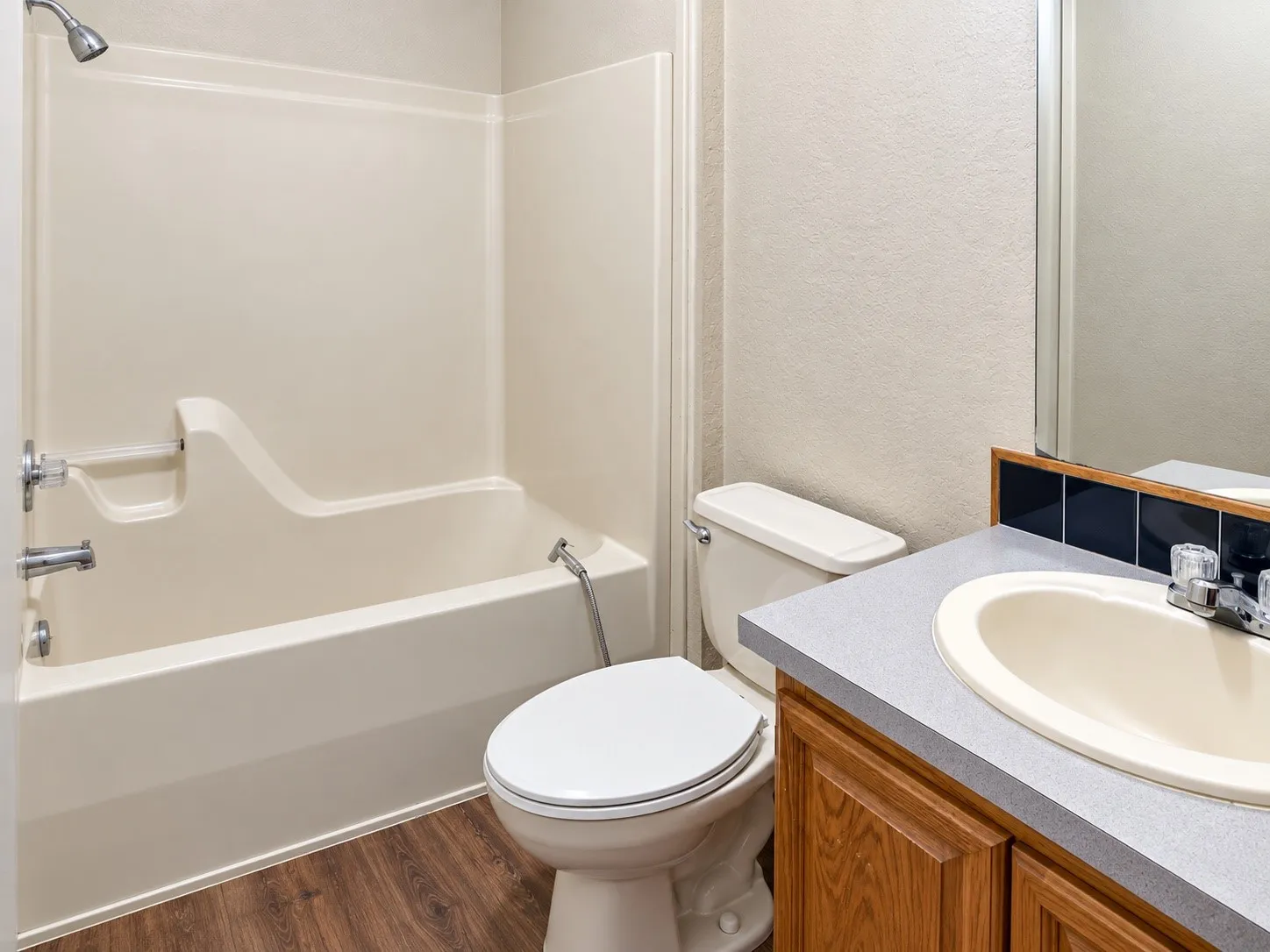 Bathroom featuring a tub/shower combination, wood-finish flooring, and a vanity with a laminate countertop and integrated sink