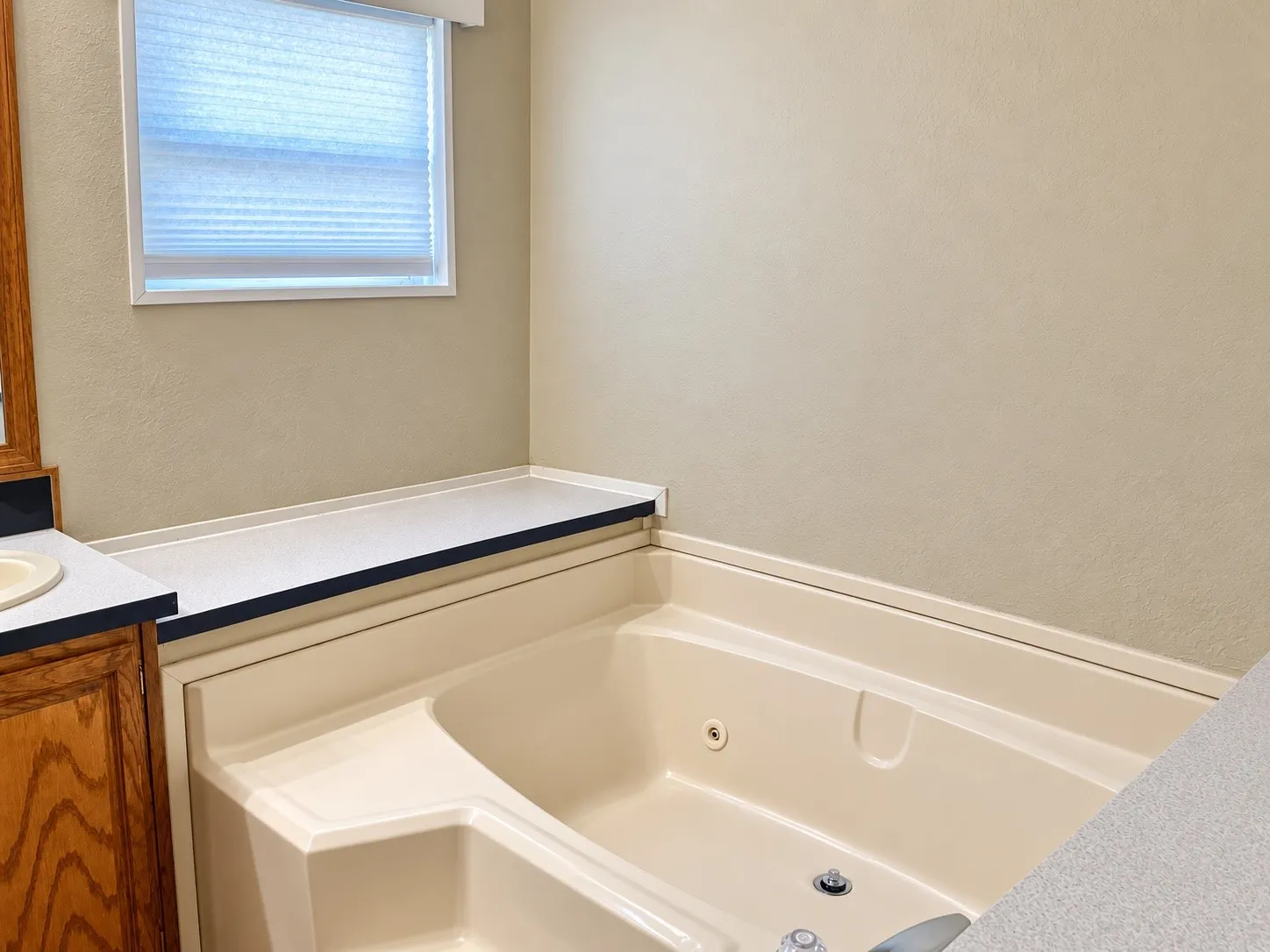 Built-in corner bathtub with integrated jets and surrounding countertop