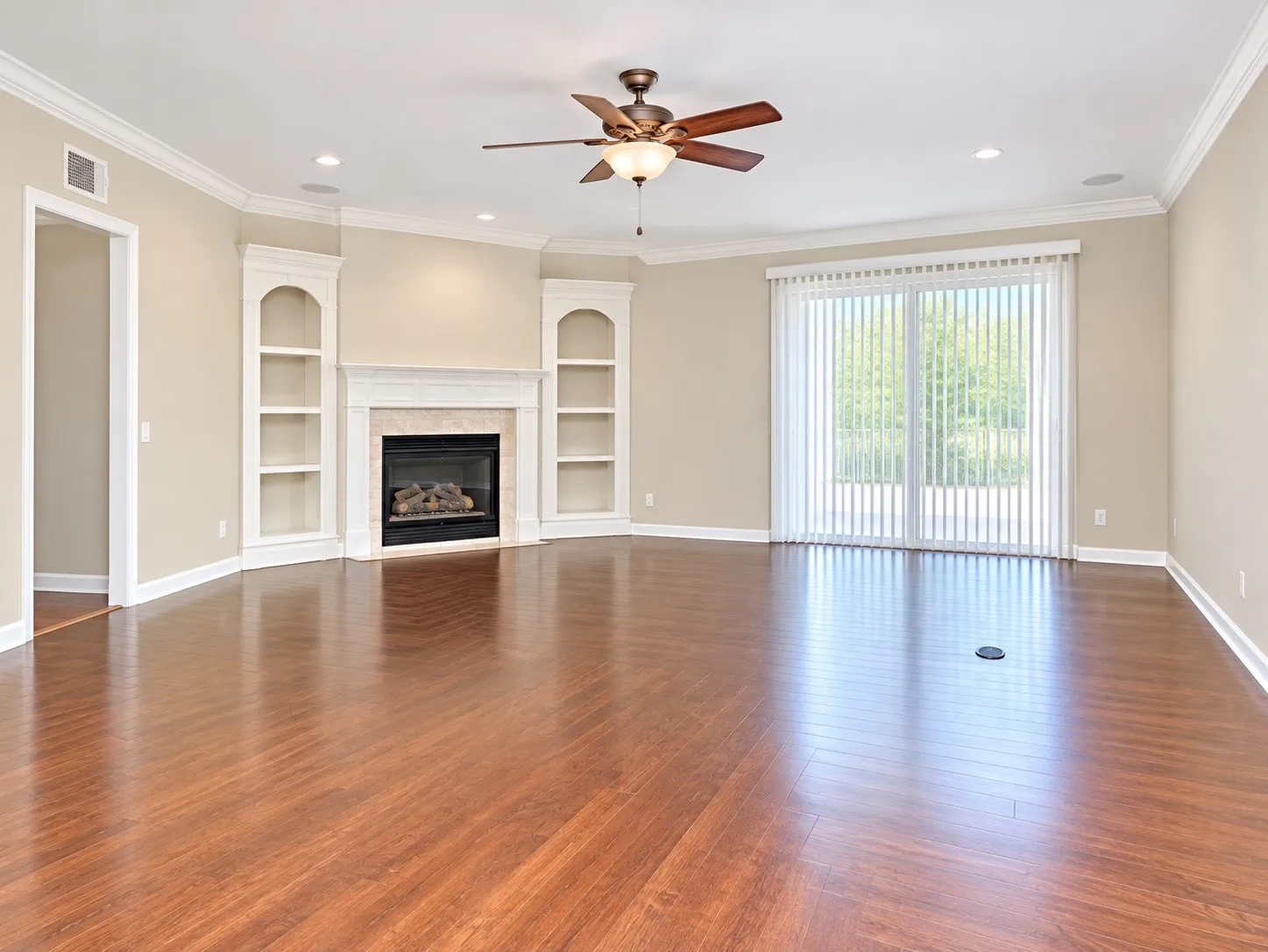 Wood-finish flooring, built-in shelving, crown molding, a fireplace, and sliding glass doors