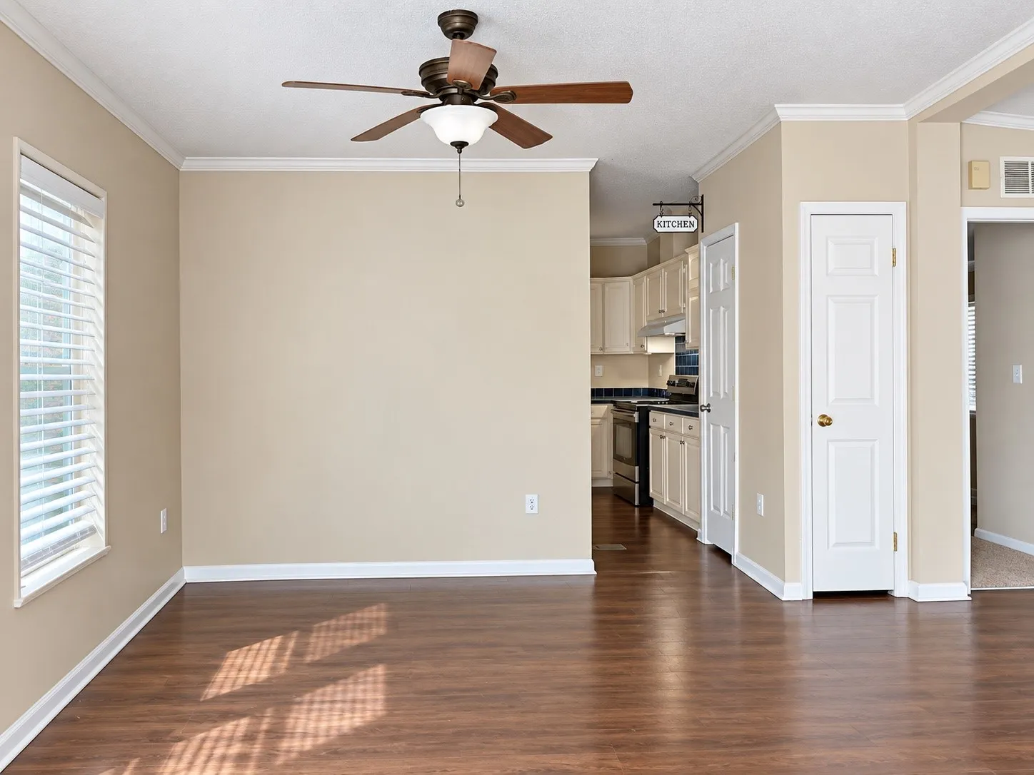Wood-finish flooring, ceiling fan, window with blinds, crown molding, and a built-in kitchen