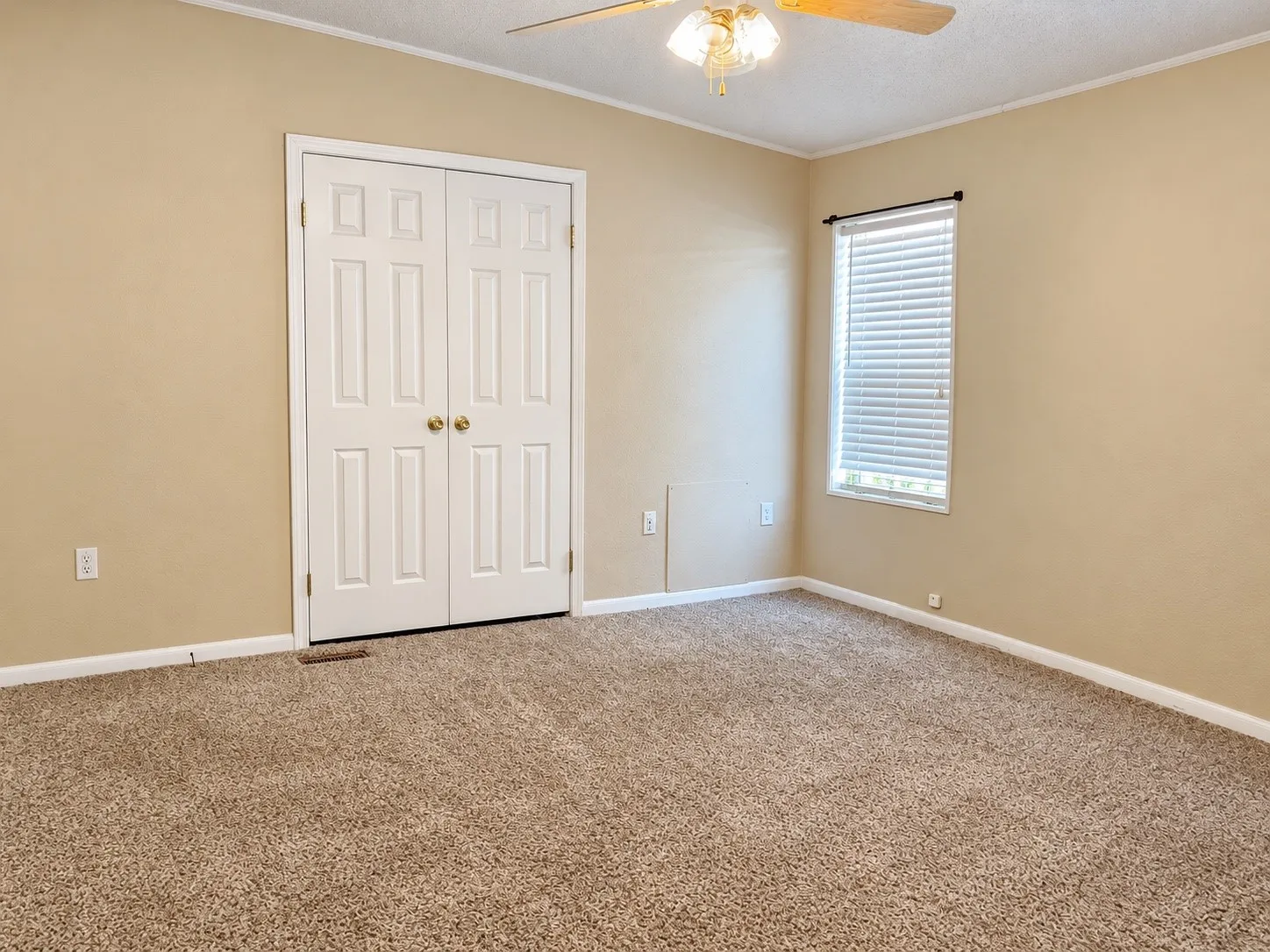 Carpeted room featuring a ceiling fan, a window with blinds, and paneled bifold closet doors