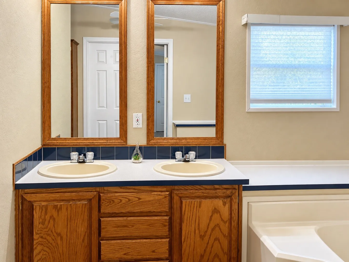 Double vanity with wood-finish cabinetry, dual sinks, and framed mirrors