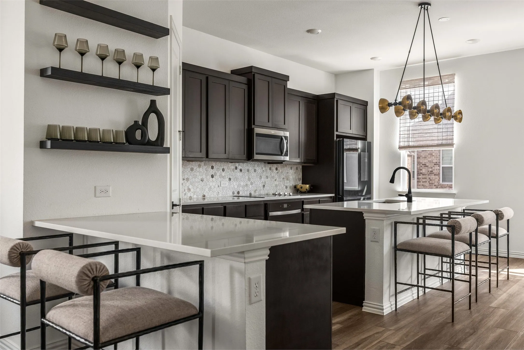 Kitchen featuring dark cabinetry, white countertops, stainless steel appliances, a tiled backsplash, and wood-finish flooring