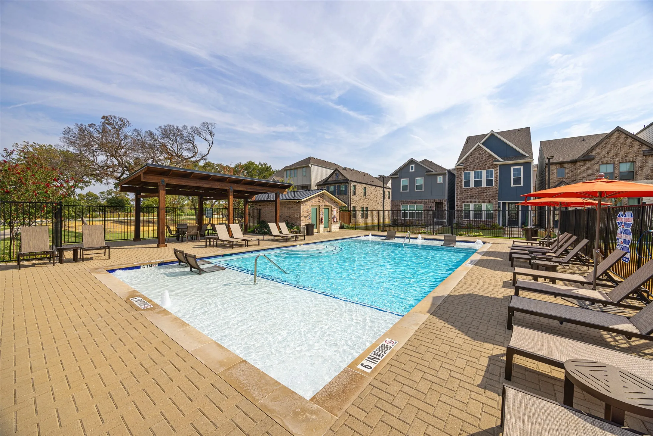 Resort-style swimming pool featuring an integrated sun shelf, surrounding paver patio, and a covered pergola