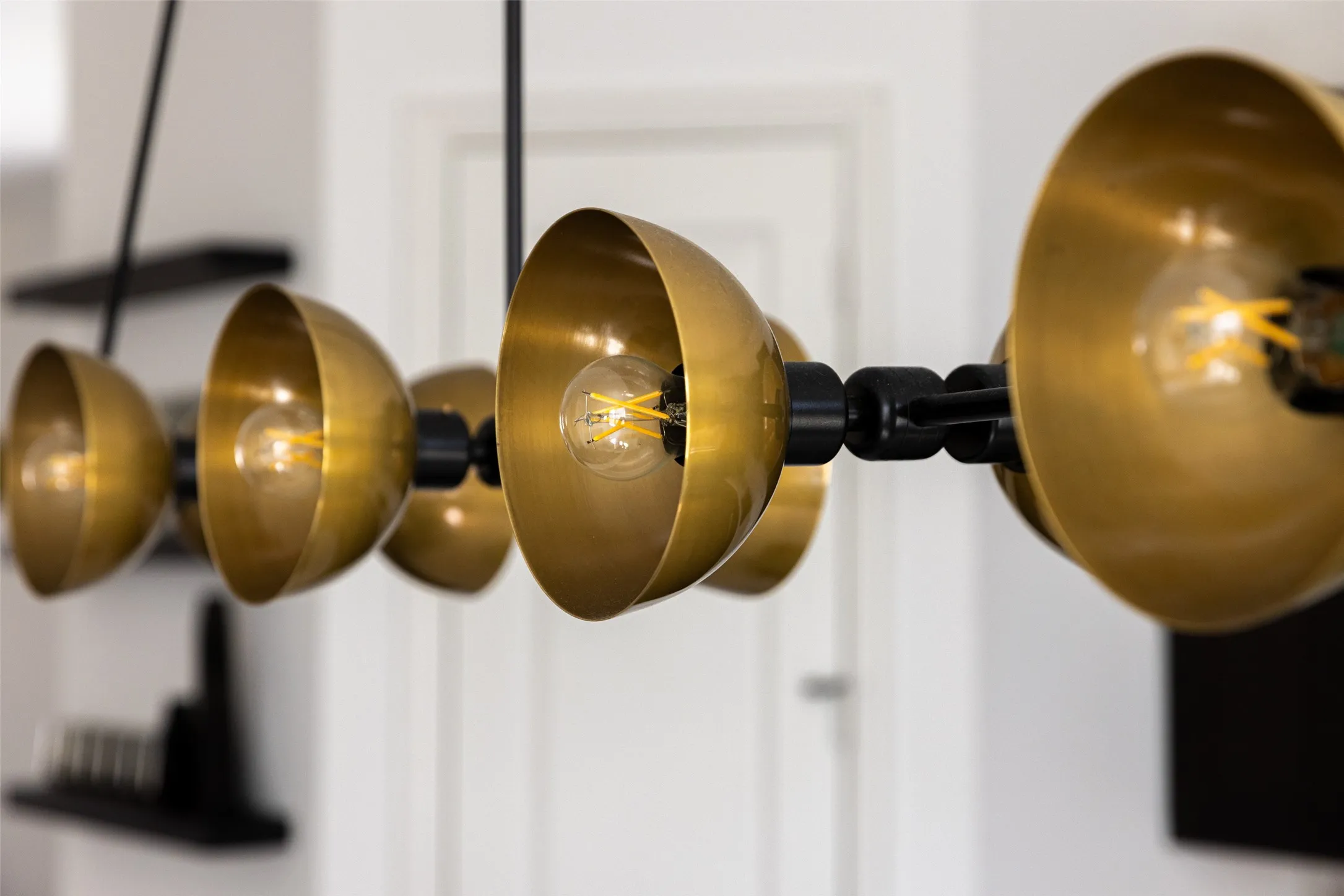 Modern multi-bulb light fixture with brass-finish shades and exposed filament bulbs