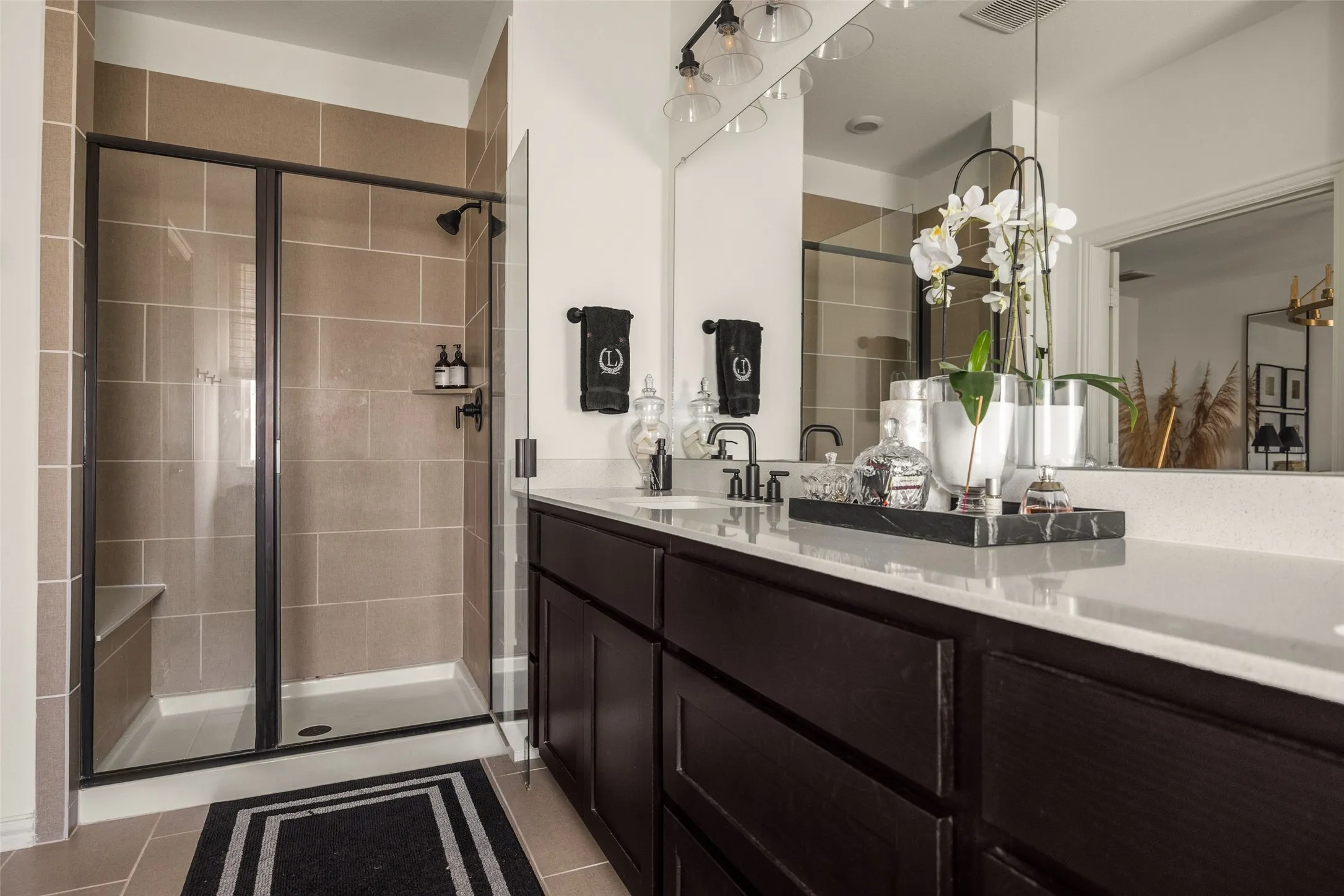 Dual vanity with stone countertop, dark wood-finish cabinetry, and matte black fixtures