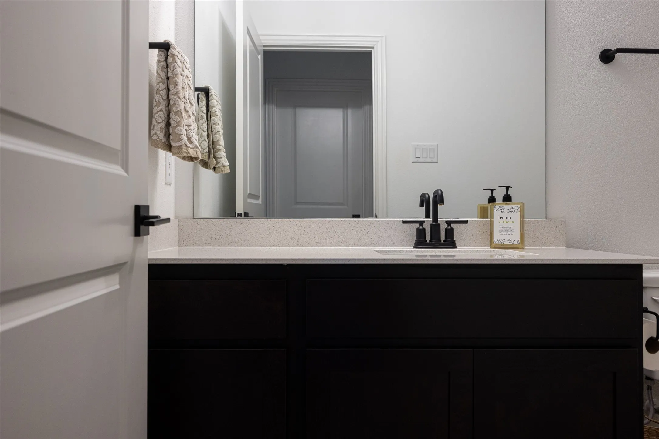 Black vanity with an integrated sink, light-toned countertop, and matte black faucet