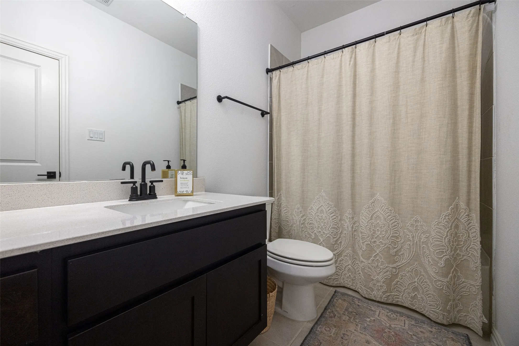 White vanity countertop with an integrated sink, dark wood-finish cabinetry, and matte black fixtures