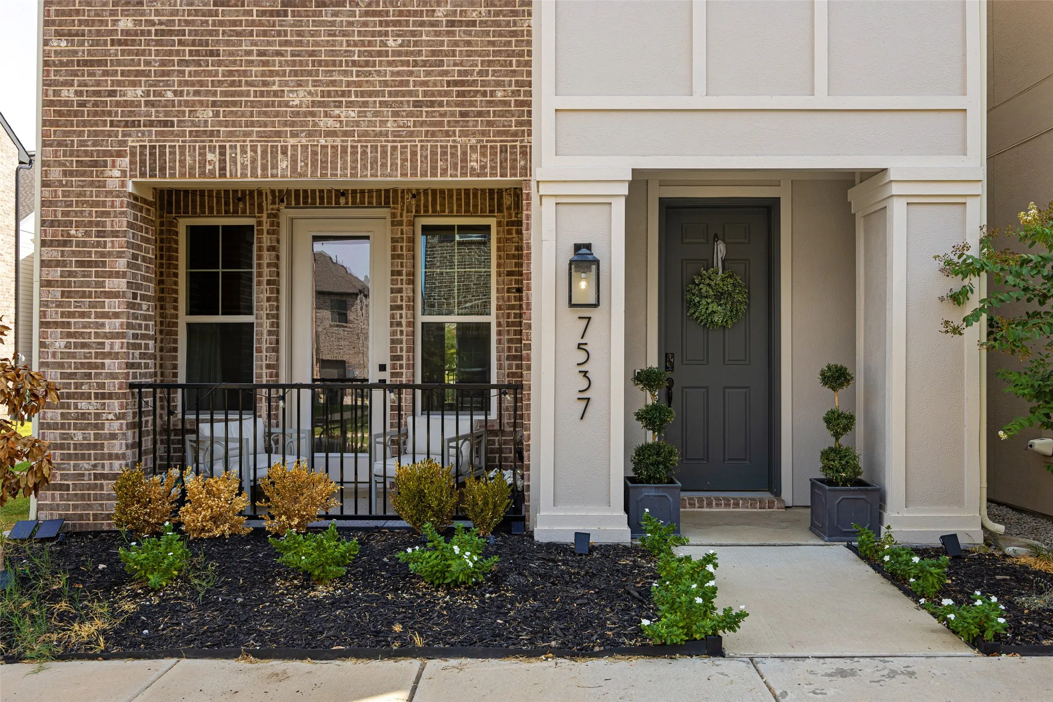 Brick exterior with a covered porch featuring black railings