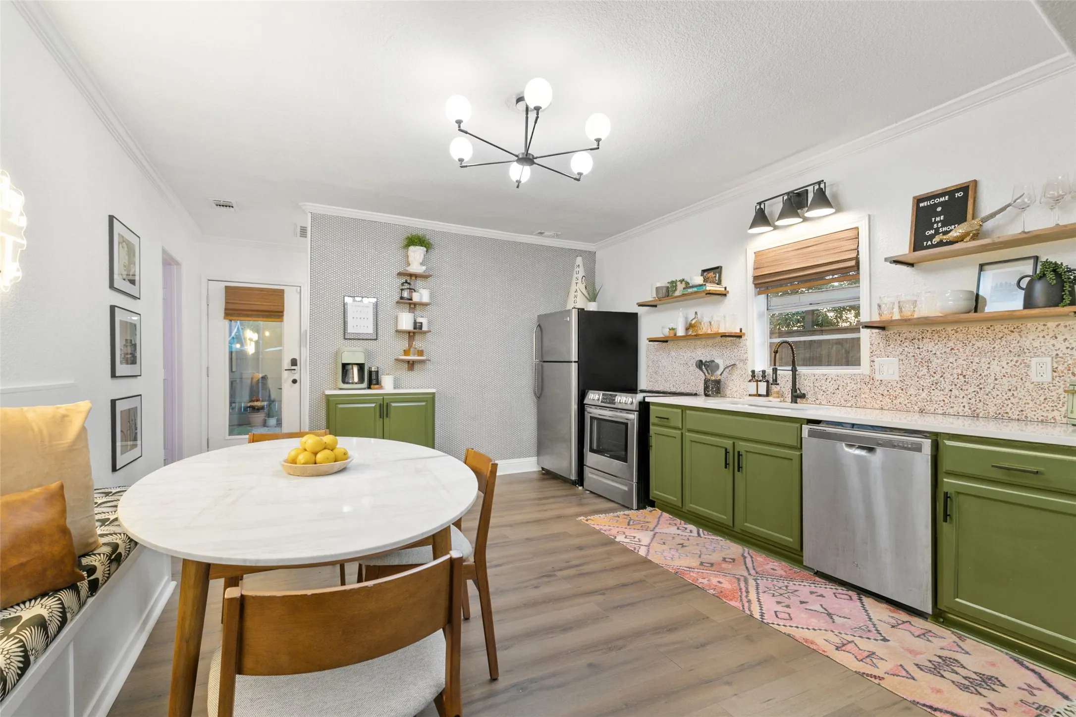 Kitchen area featuring wood-finish flooring, green cabinetry, stainless steel appliances, and a white countertop