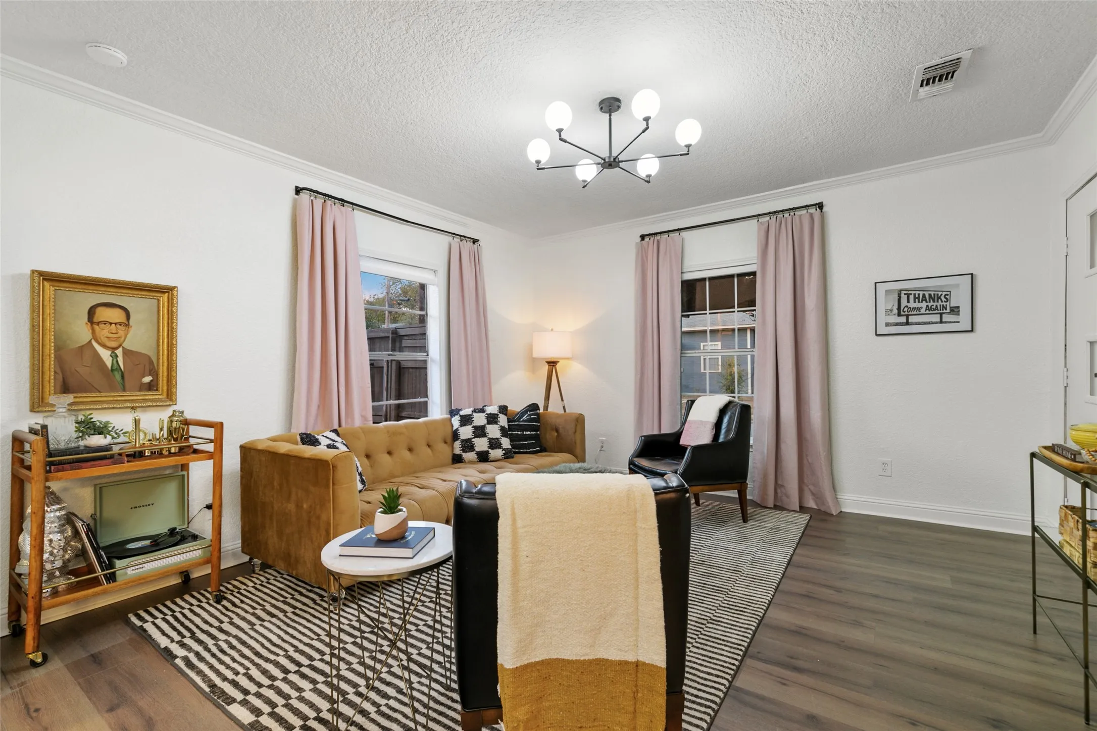 White wall finishes with crown molding, wood-finish flooring, and a modern chandelier