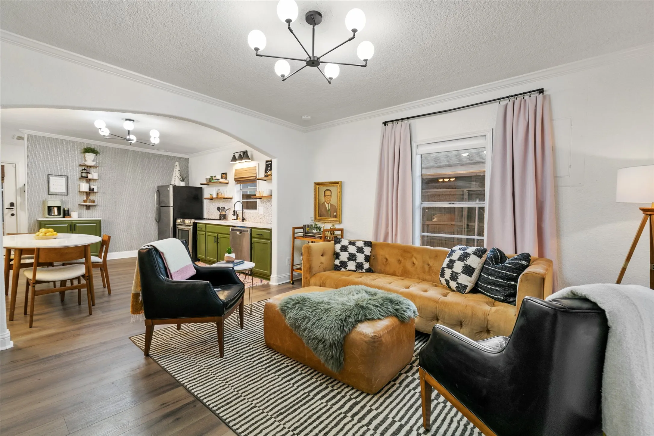 Open concept living area with wood-finish flooring, an arched doorway, and crown molding