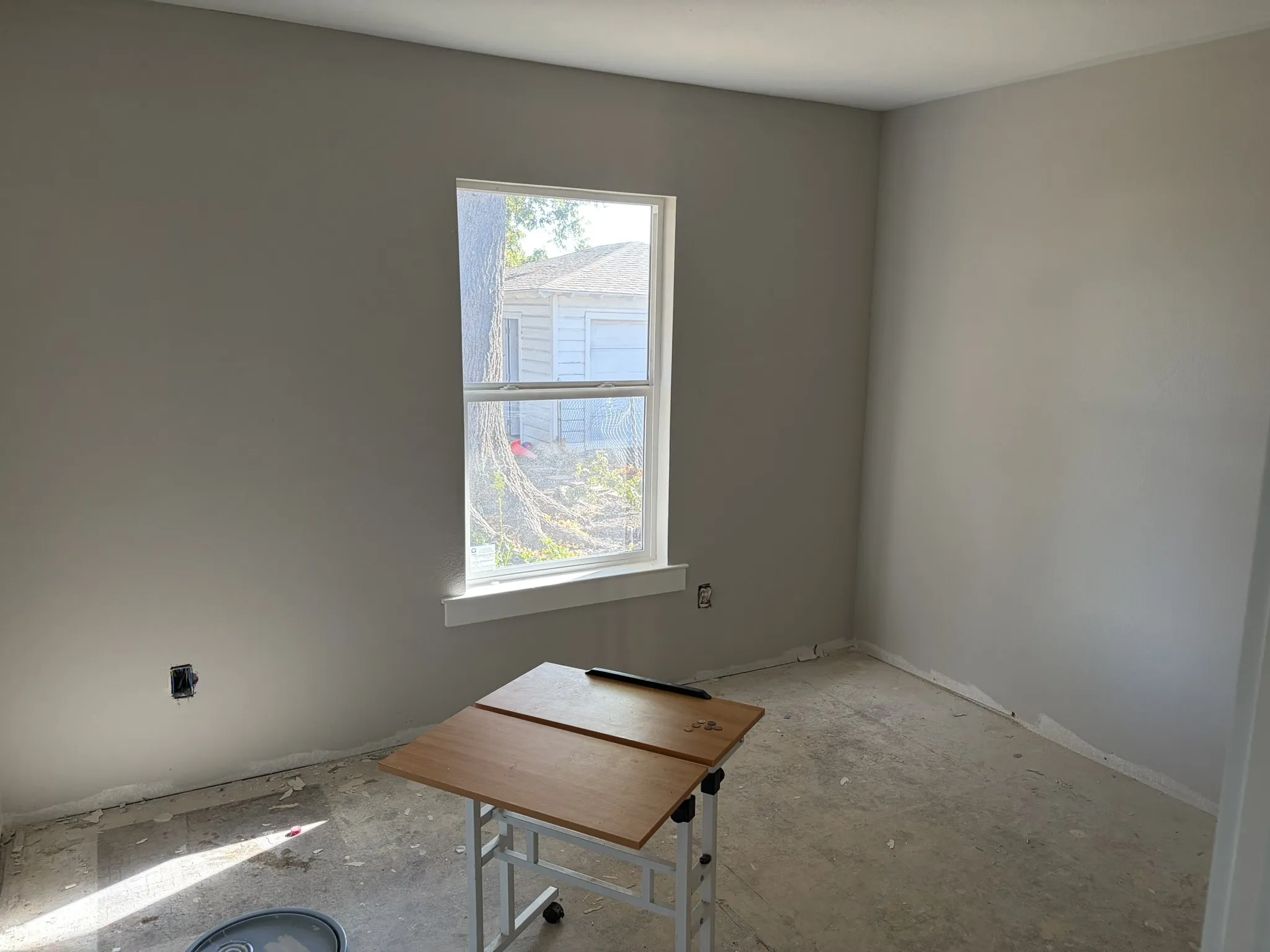 Bright, unfurnished room with large double-hung window featuring natural light and outdoor visibility
