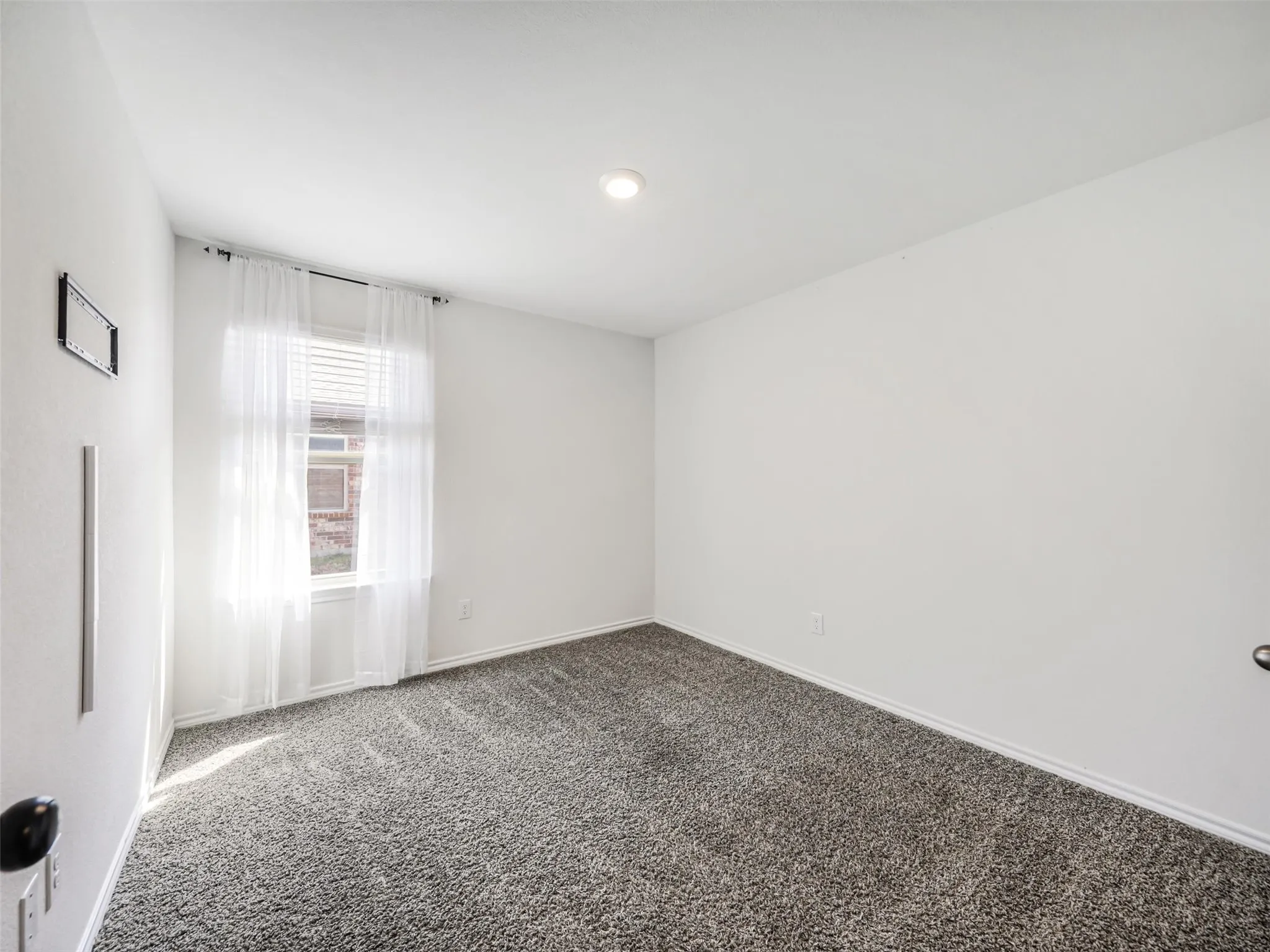Carpeted room with a single window, white walls, and a recessed ceiling light