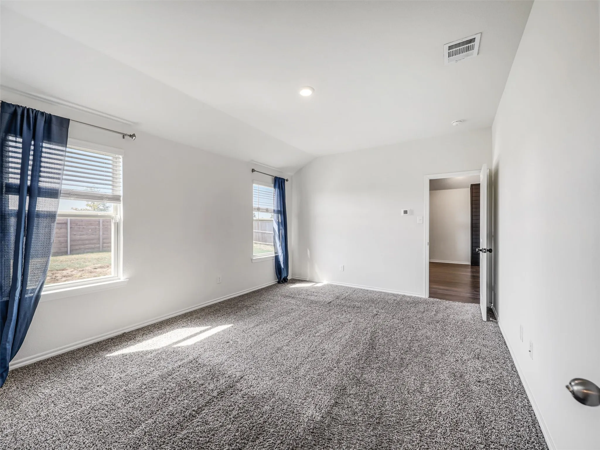 Plush carpet flooring, two windows, recessed lighting, white walls, and a white ceiling