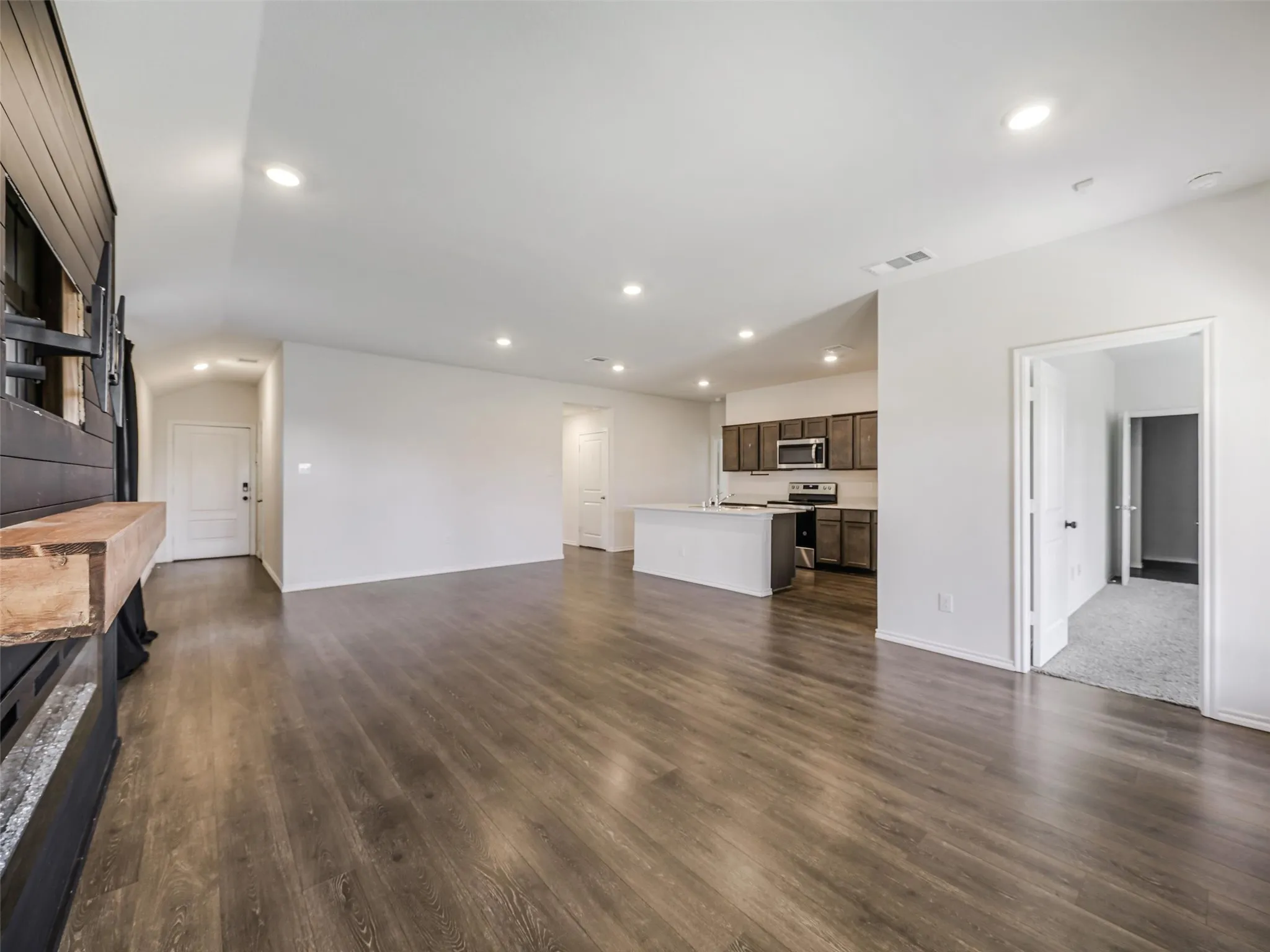 Open-concept living space with wood-finish flooring, recessed lighting, and a built-in electric fireplace
