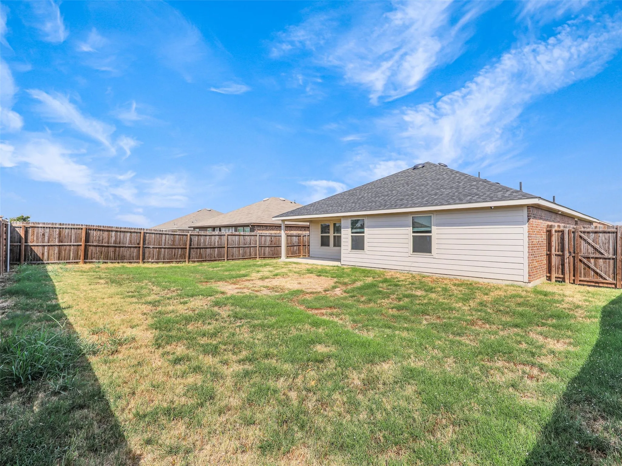 Expansive backyard featuring a privacy fence, brick and siding exterior, and a shingle roof