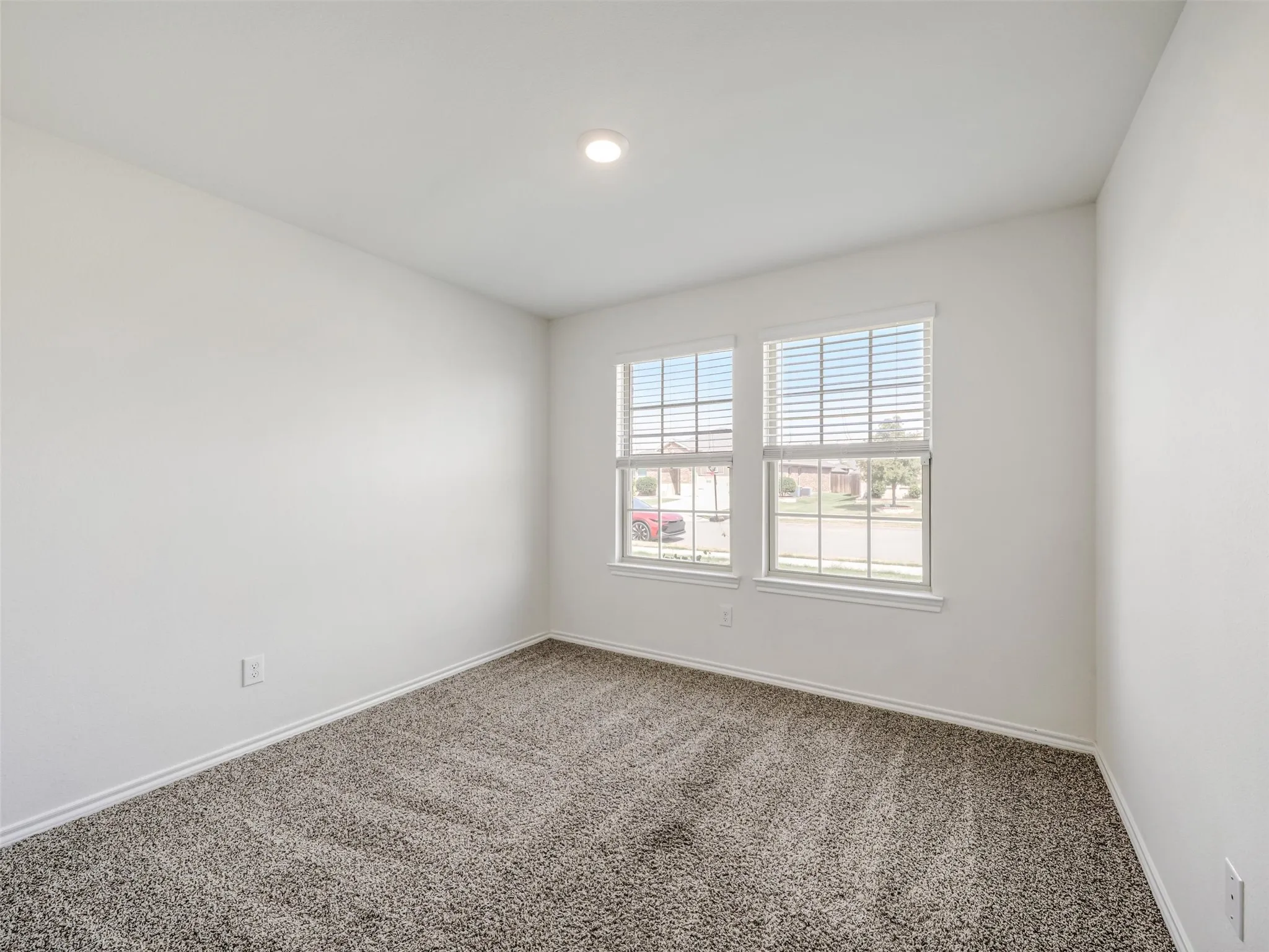Recessed ceiling lighting, white painted walls, textured carpeting, and two pane windows with horizontal blinds