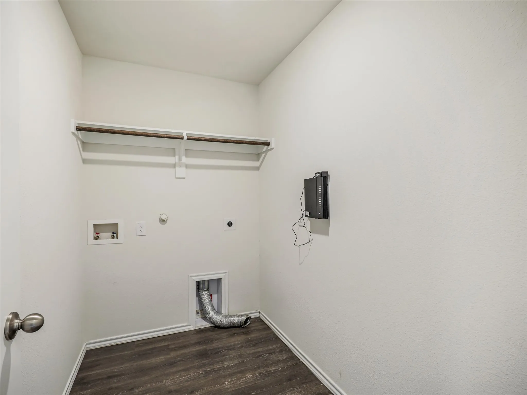 Utility room with wood-finish flooring, a wall-mounted clothing rod, and appliance hookups