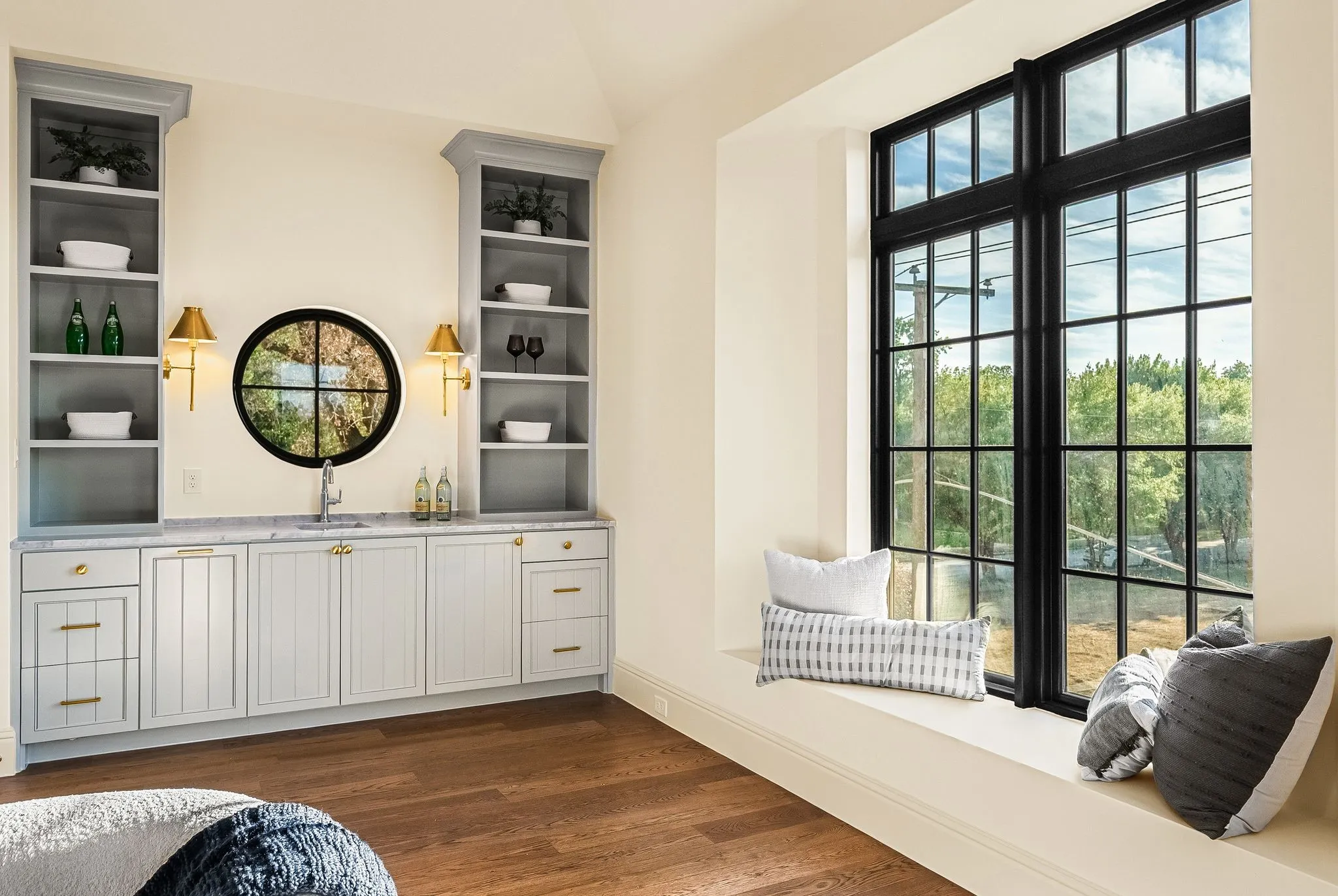 Built-in wet bar with a circular window, integrated cabinetry, and stone countertop