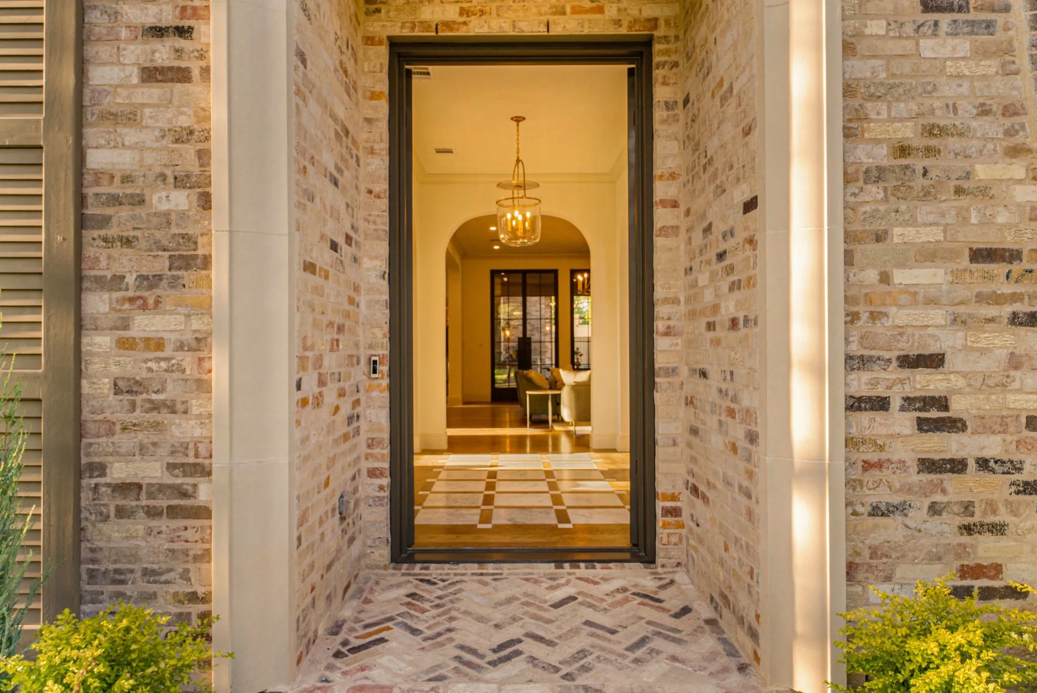 Brick exterior with stone accents, herringbone pattern brick entry, arched interior doorway, and a decorative interior light fixture