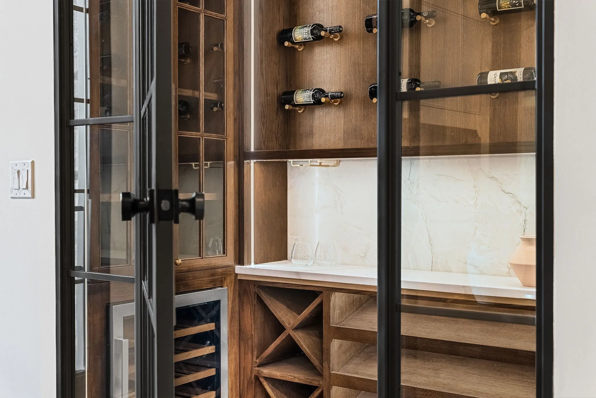 Built-in wine storage featuring wood-finish cabinetry, glass-front doors, integrated lighting, and a beverage cooler