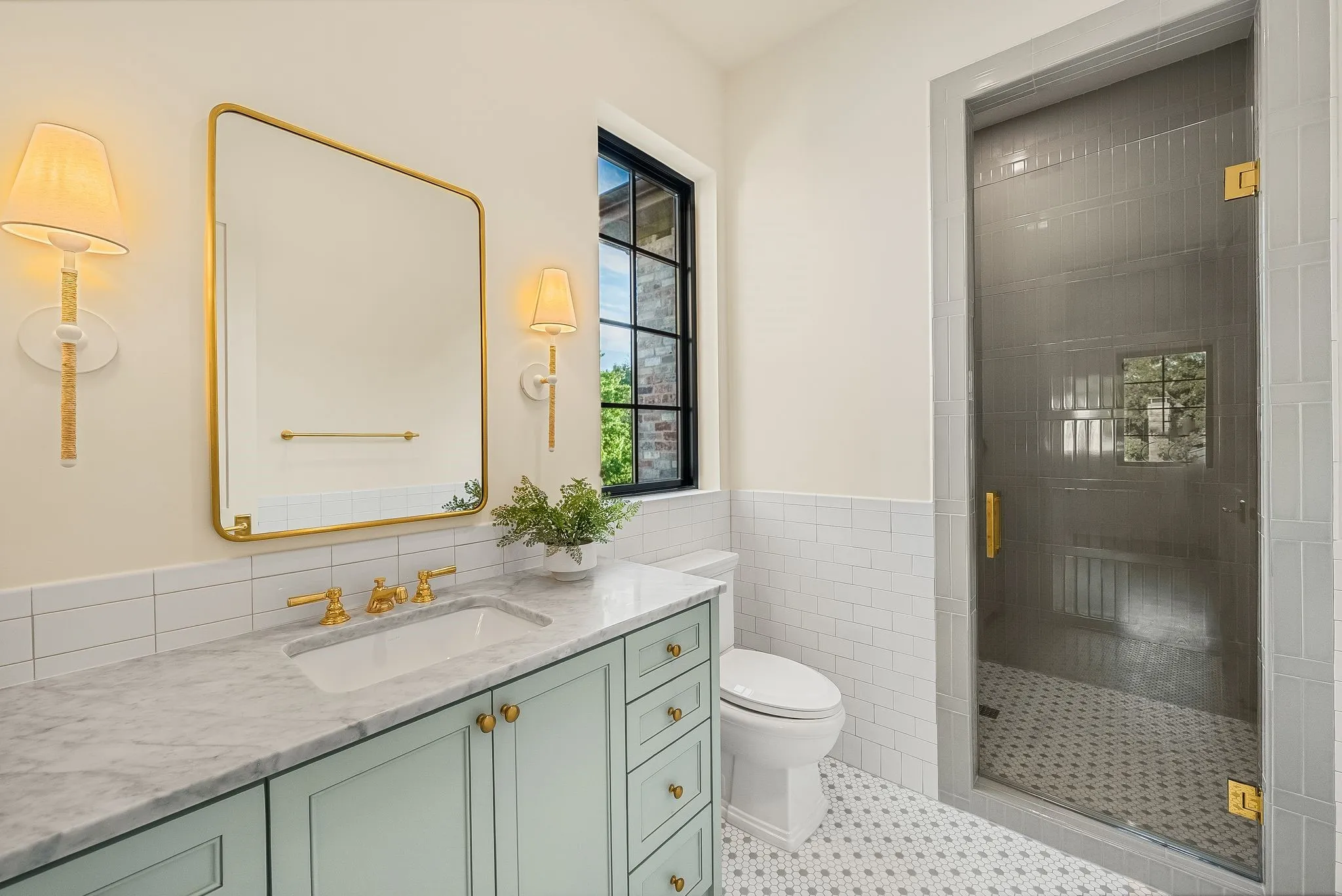 Light blue vanity with brass hardware, undermount sink, and stone countertop