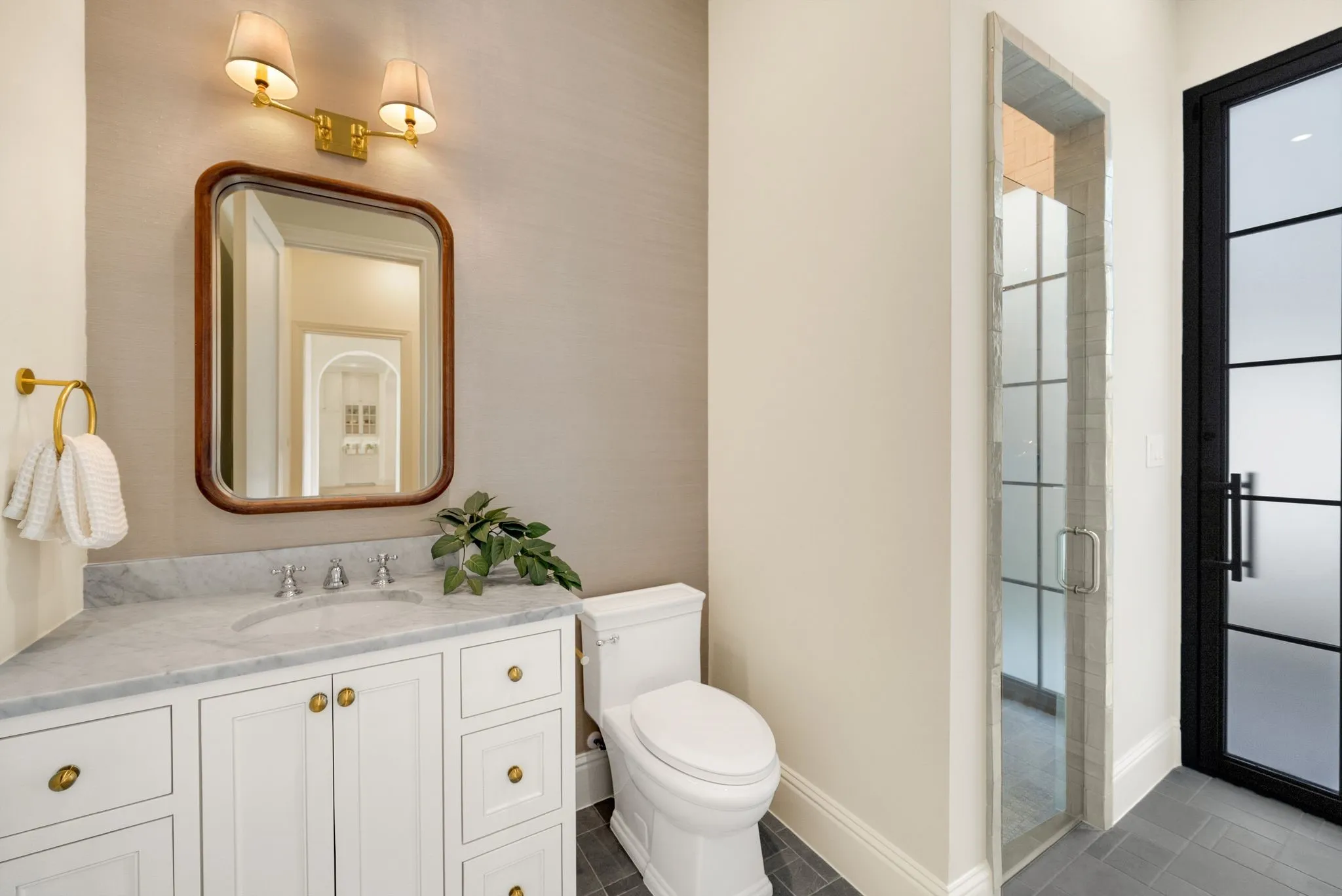 White vanity with brass hardware, marble-finish countertop, and undermount sink