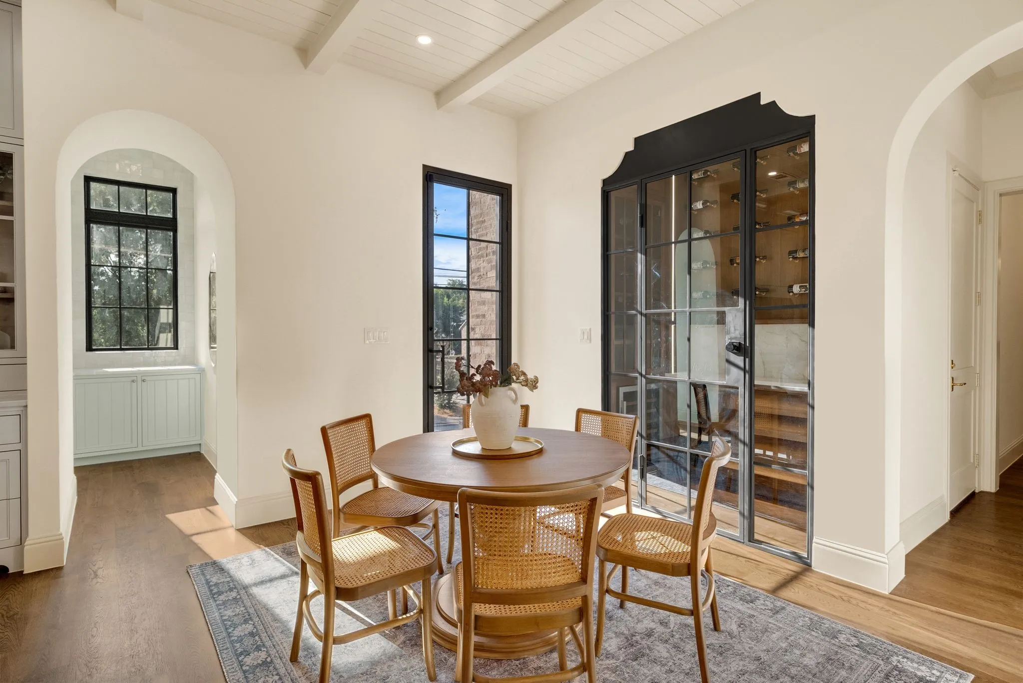 Wood-finish flooring, white coffered ceiling, and an arched entryway